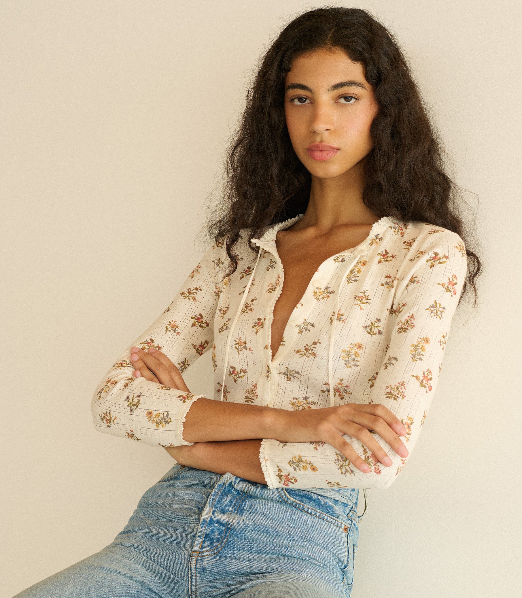Woman wearing a floral blouse and jeans against a plain background 3
