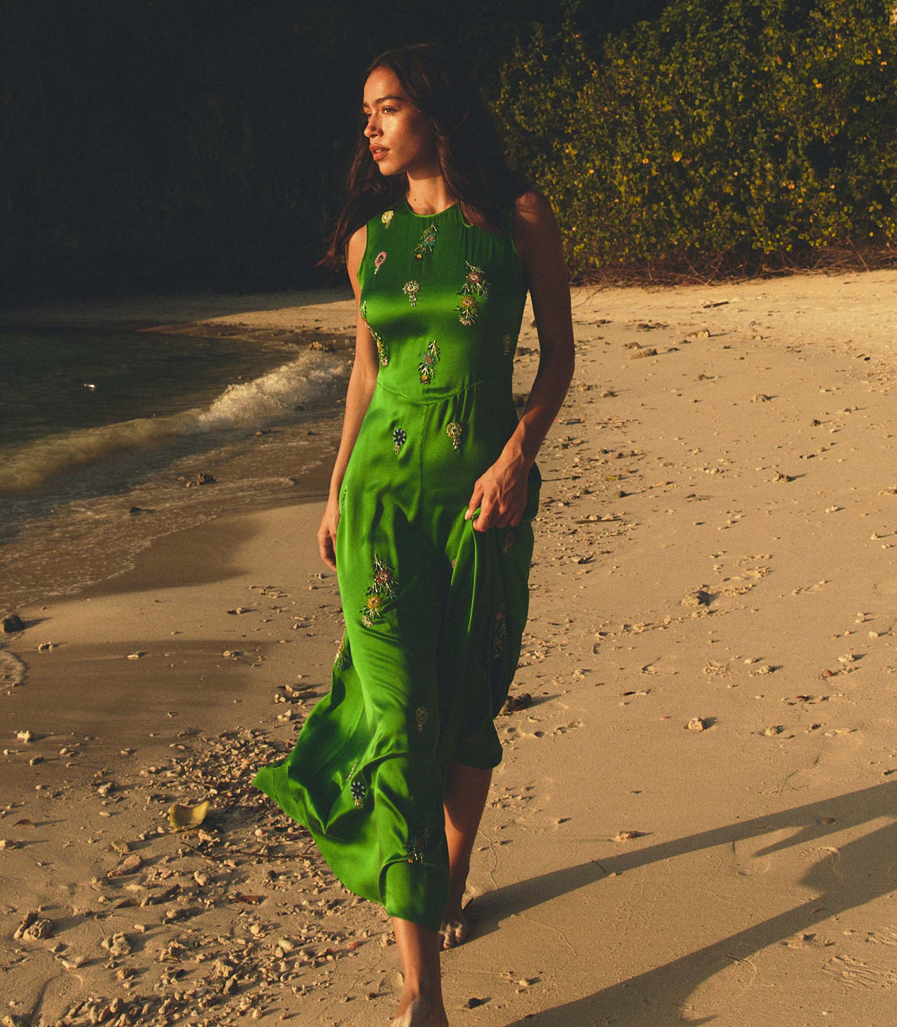 Woman in a green dress walking on a beach at sunset 1
