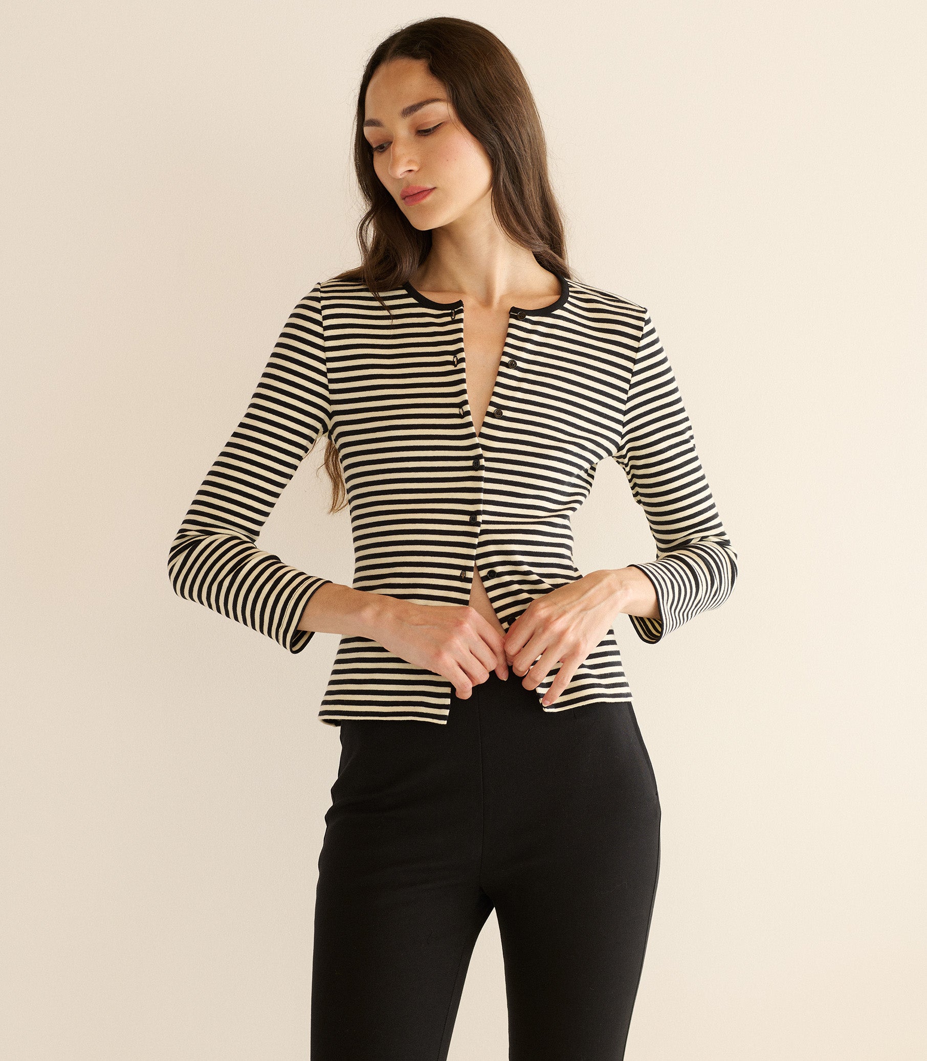 Woman wearing a black and white striped long-sleeve top against a beige background 1
