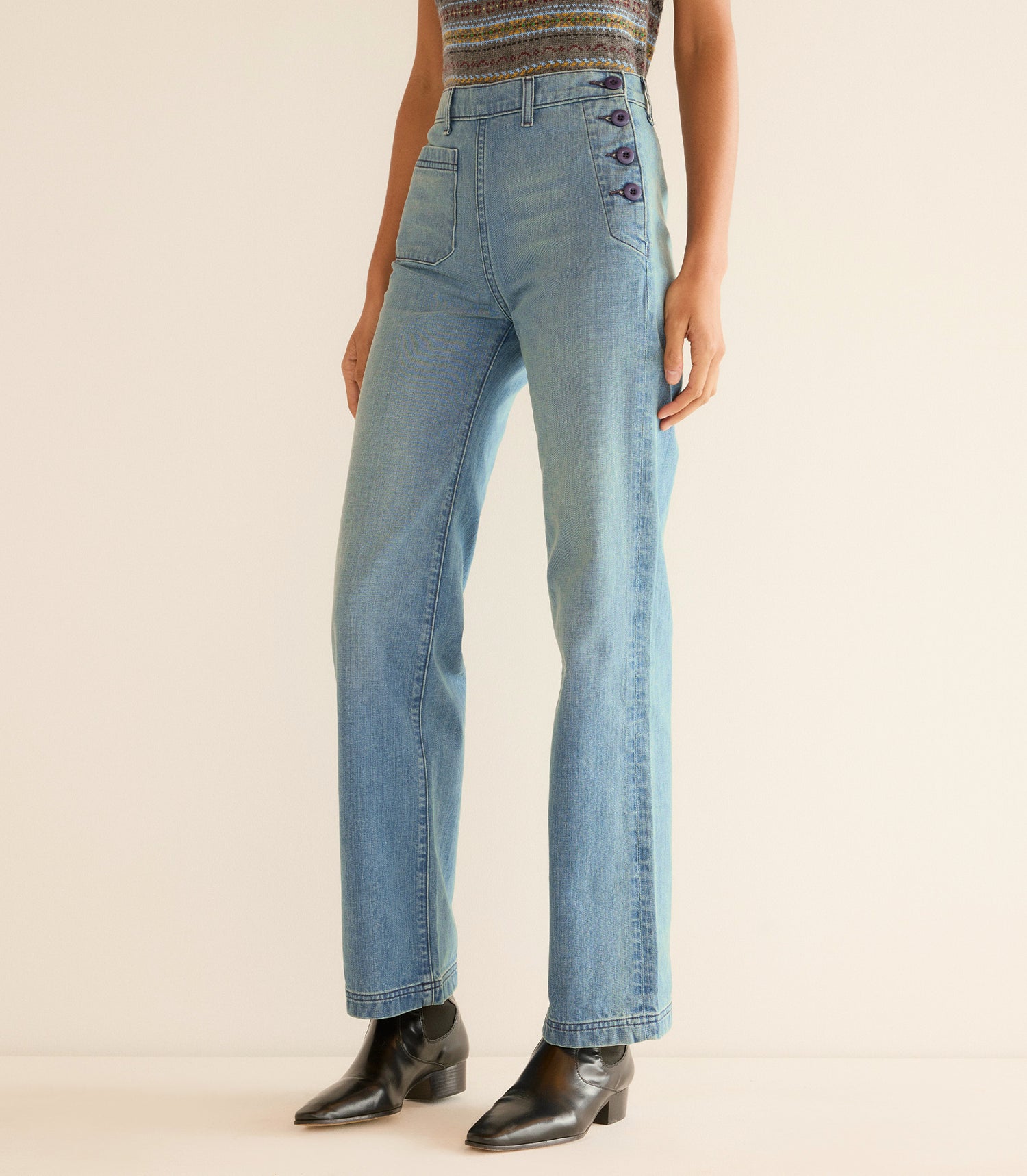 Person wearing light blue jeans on a beige background