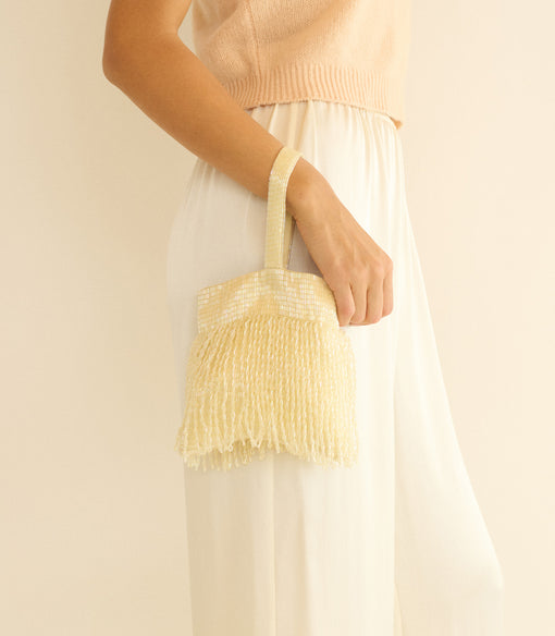 Person holding a champagne handbag against a plain background