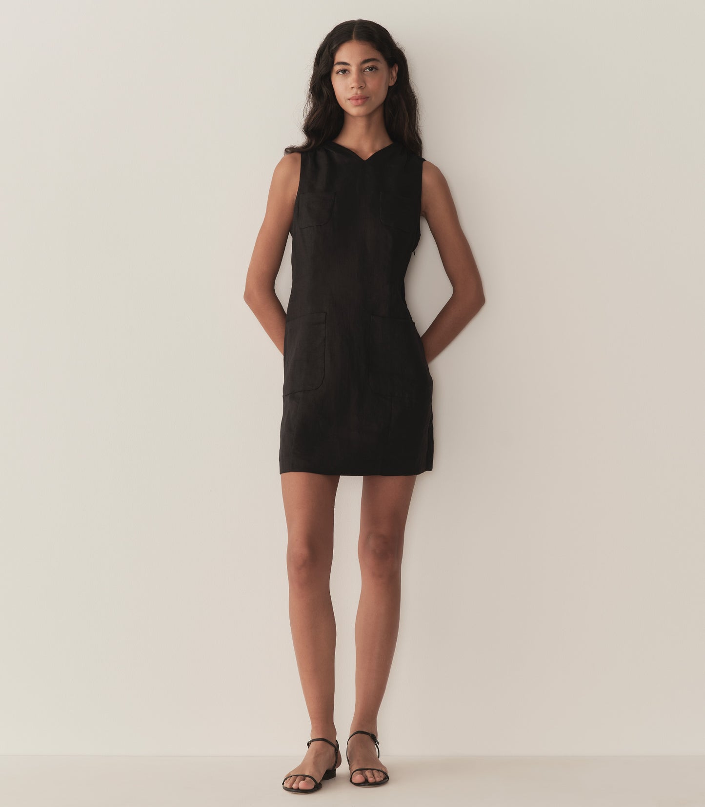 Rocio is wearing a black sleeveless linen mini dress.
