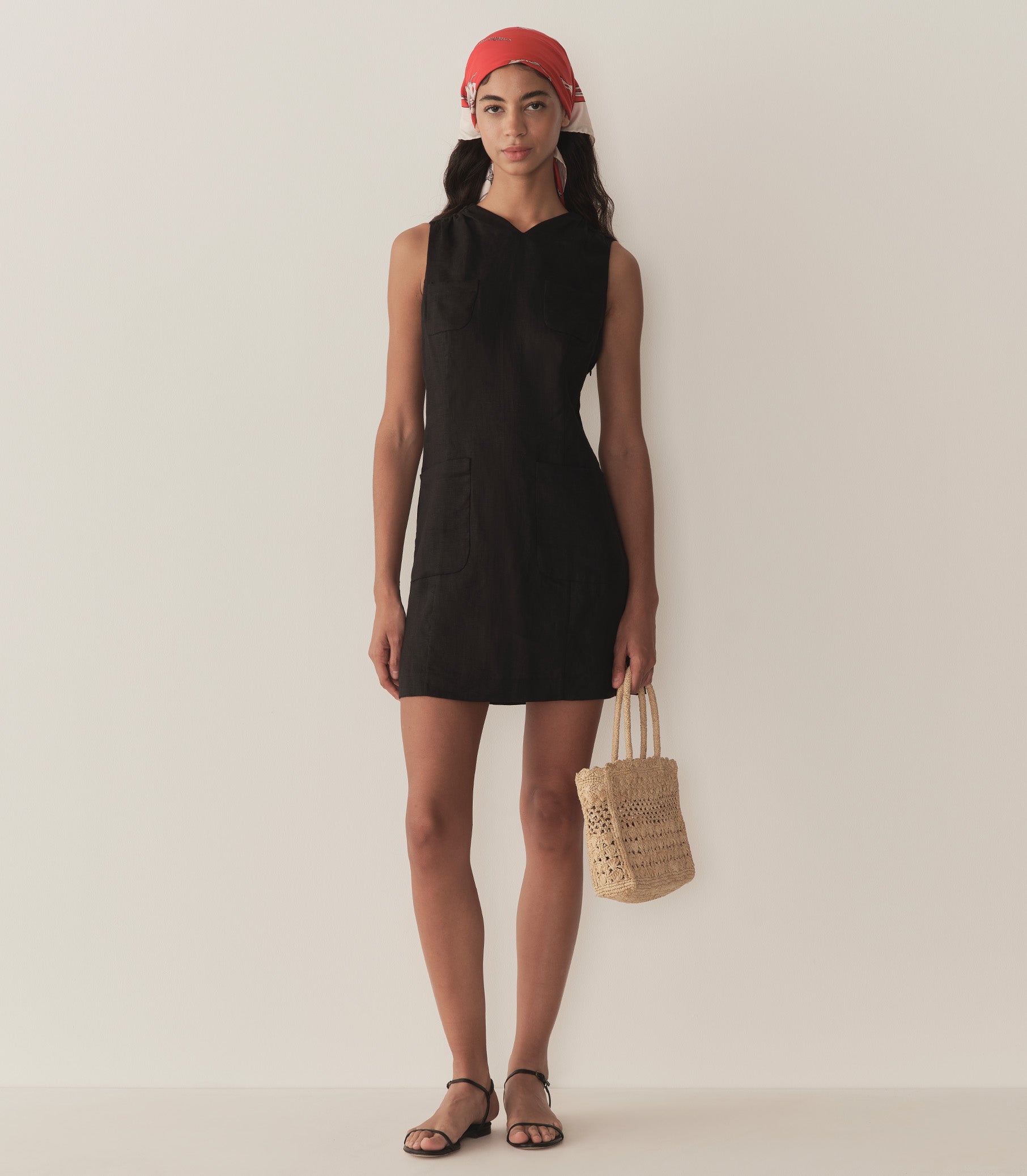 Rocio is wearing a black sleeveless linen mini dress paired with a bandana, sandals, and bag. 3
