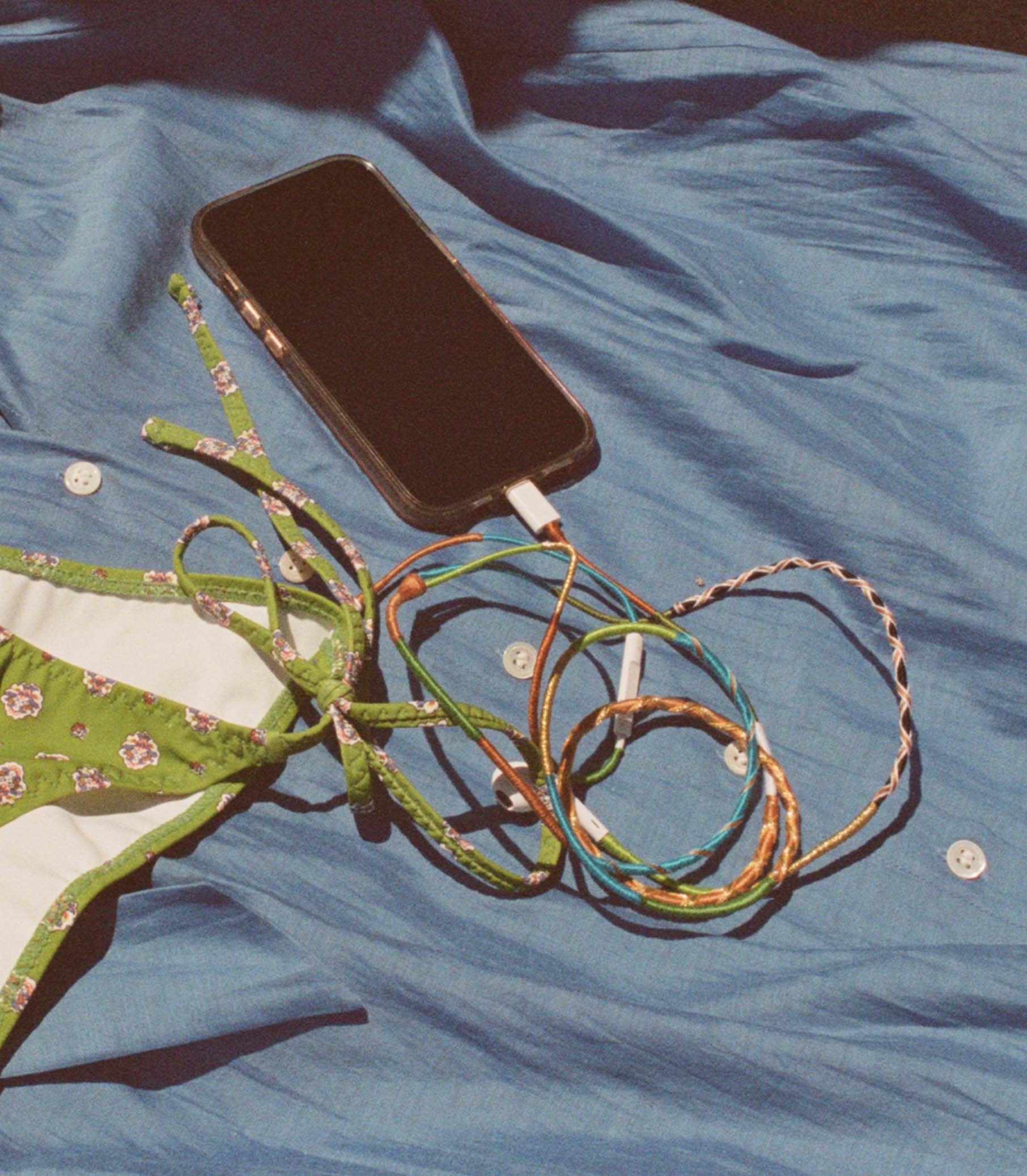 Phone with rainbow headphones on a blue fabric background