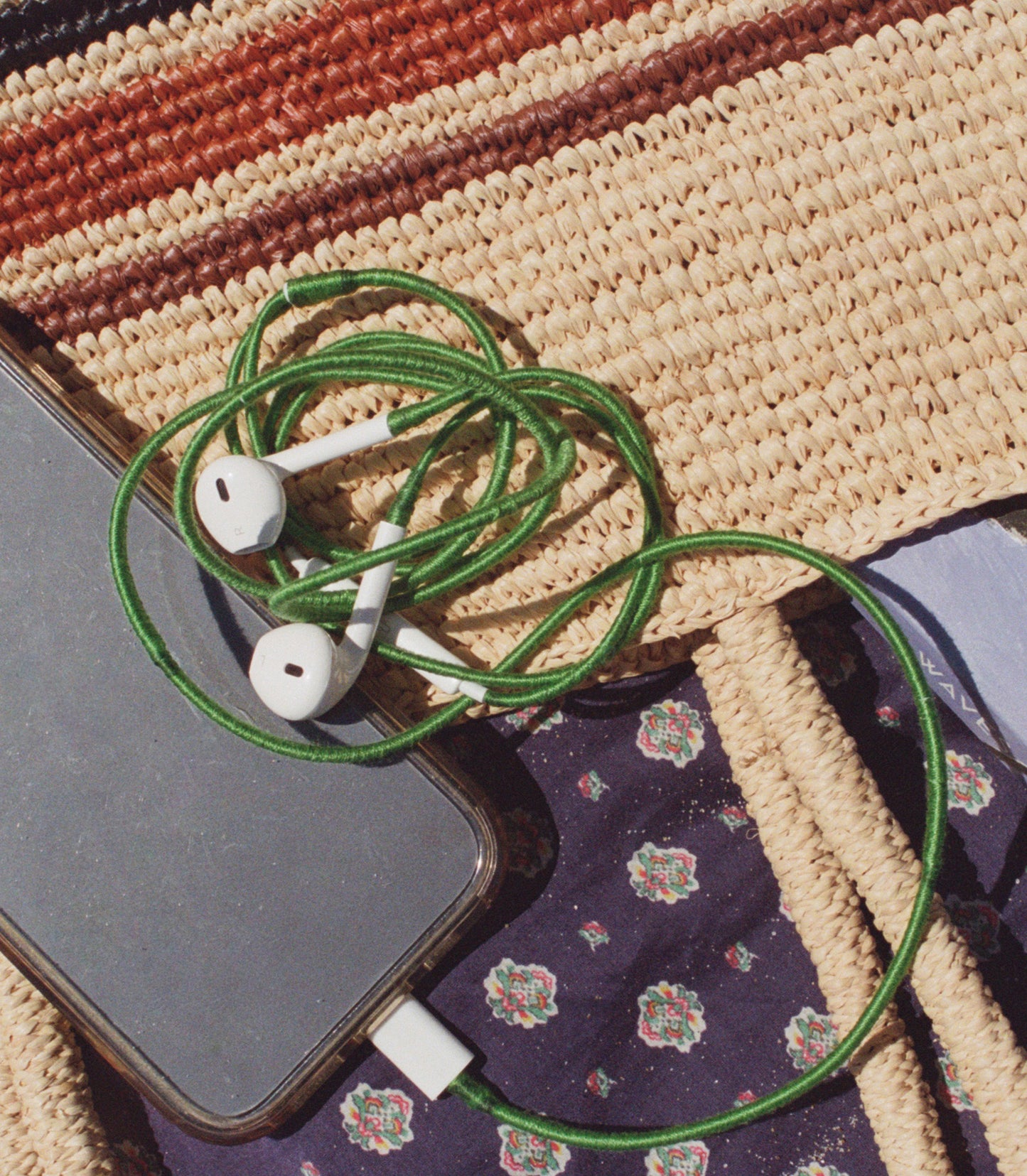 Cellphone with gren earphones on a woven bag