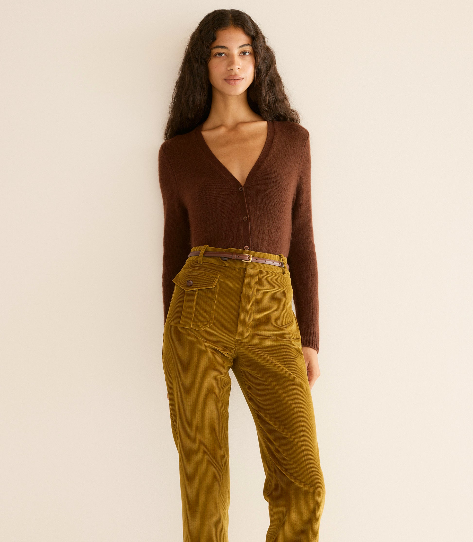 Woman wearing a brown sweater and mustard yellow pants against a beige background 2
