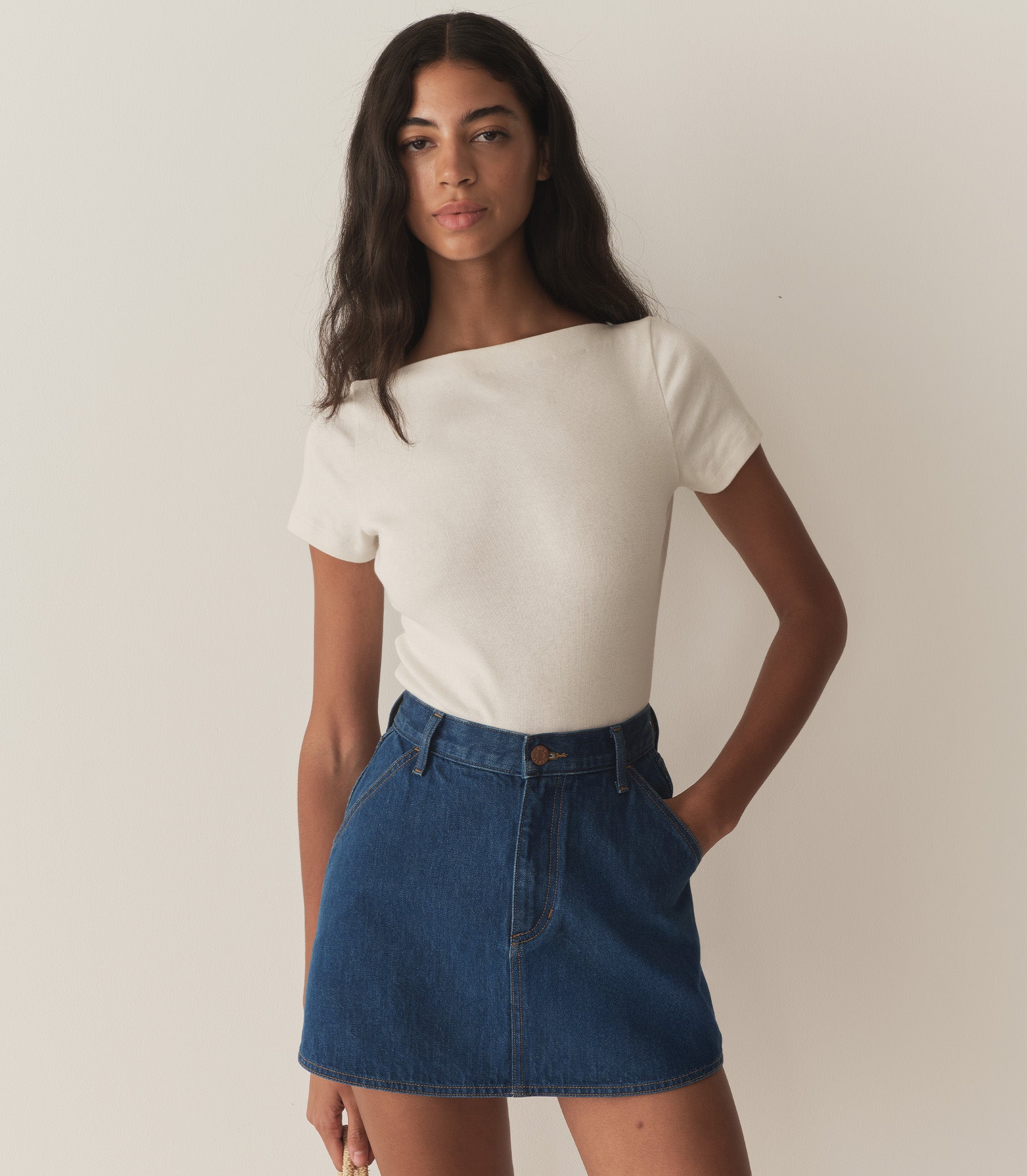 Rocio is wearing a denim A-Line skirt paired with a white top and red flats. 2
