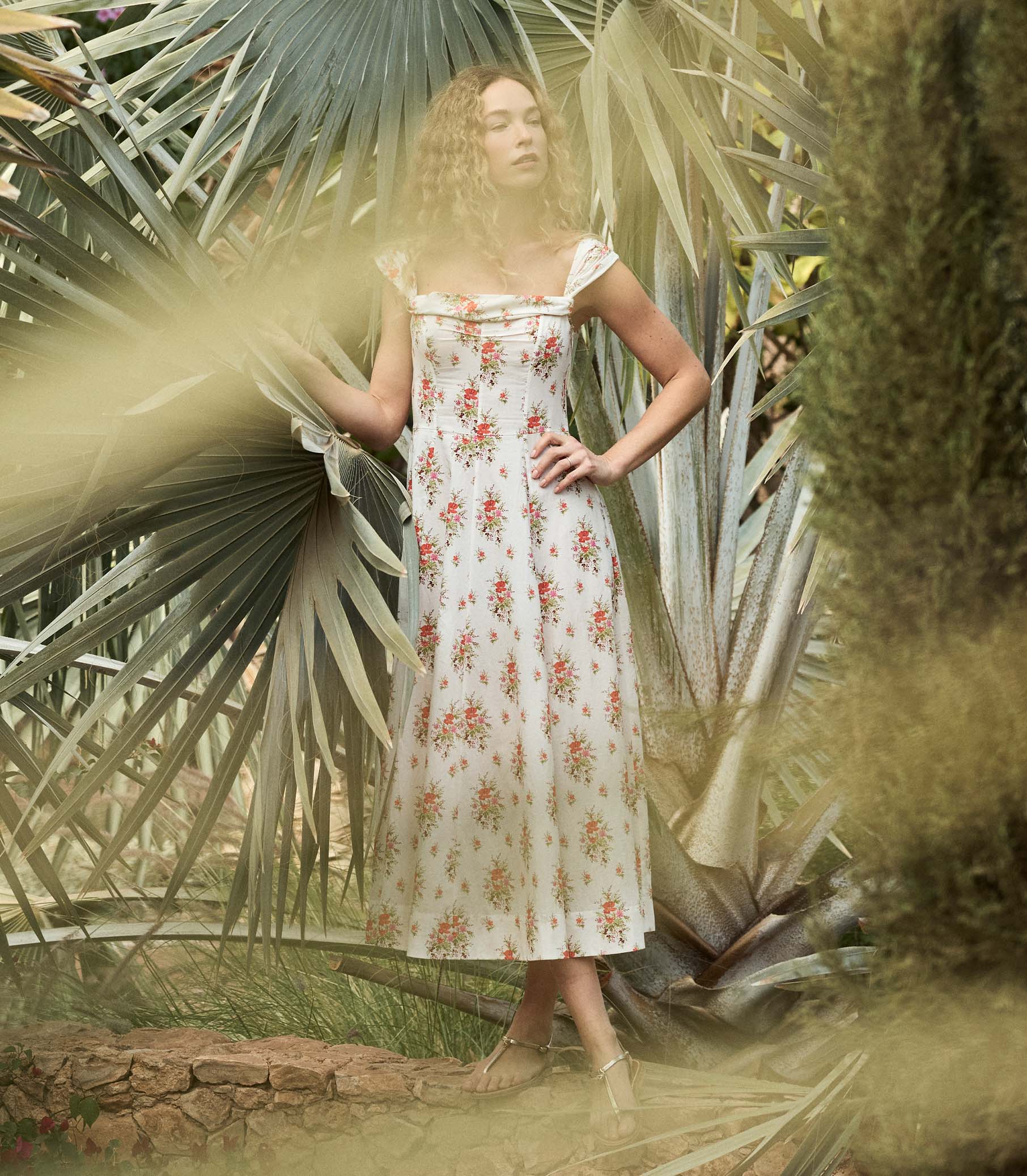 Woman in a floral dress standing among tropical plants