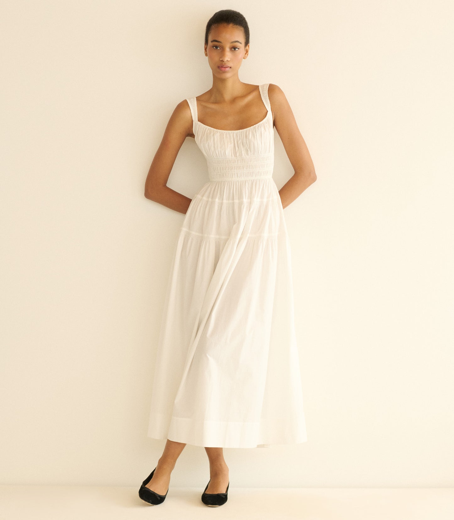 Woman wearing a long white dress against a plain background