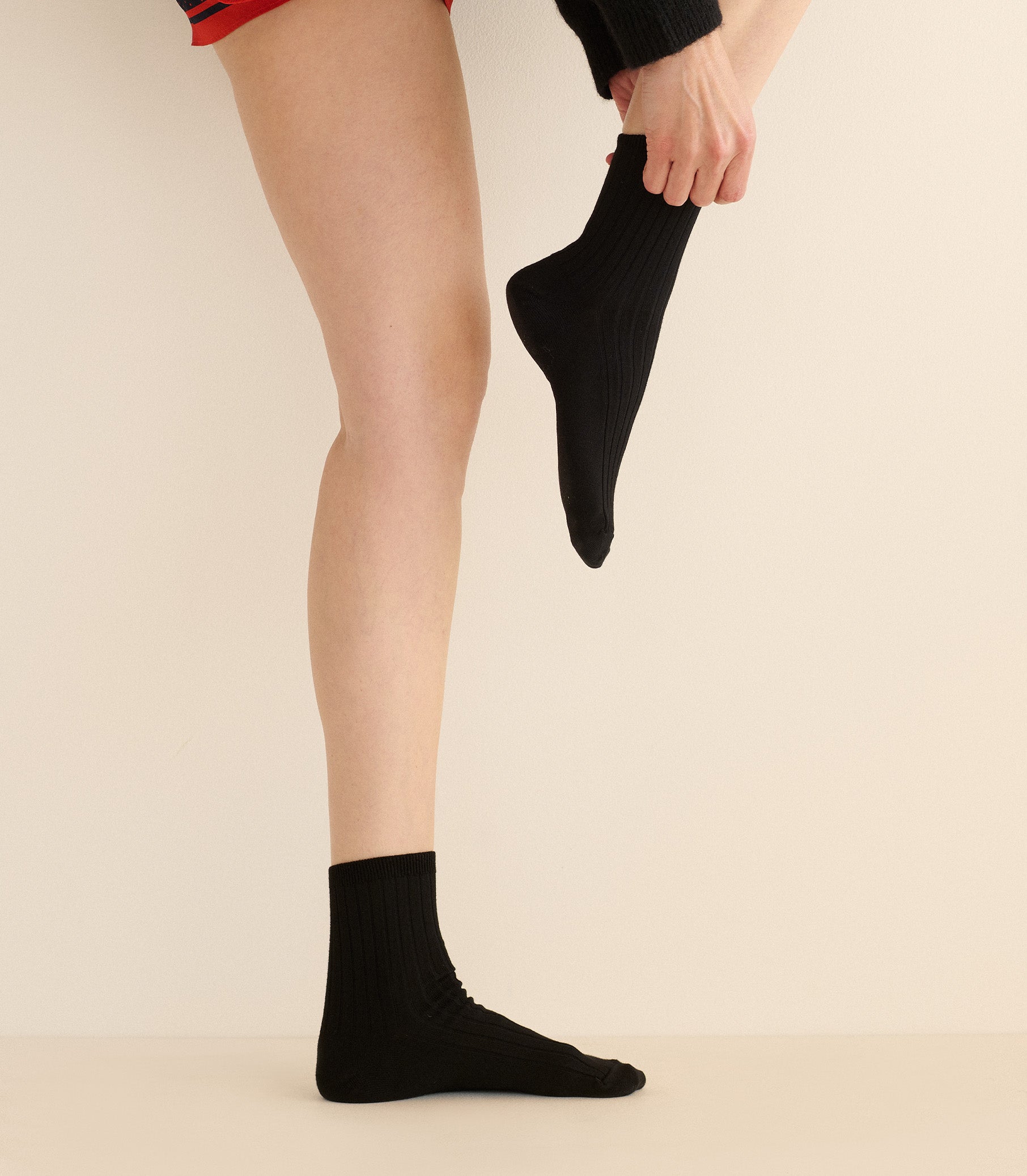 Person wearing black socks against a beige background