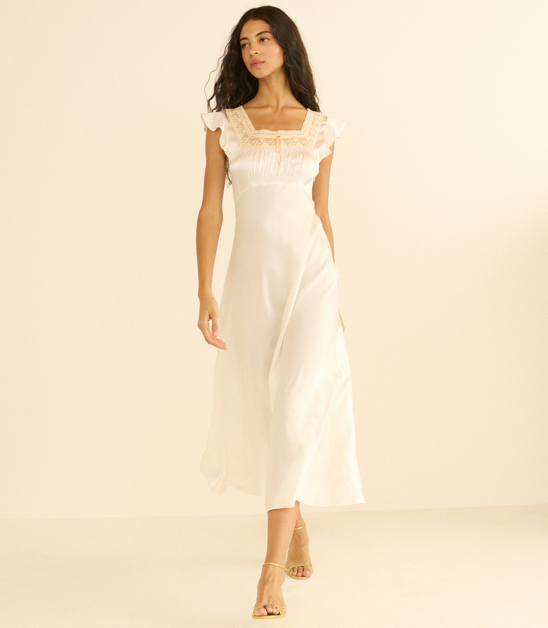Woman wearing a white satin nightgown against a beige background