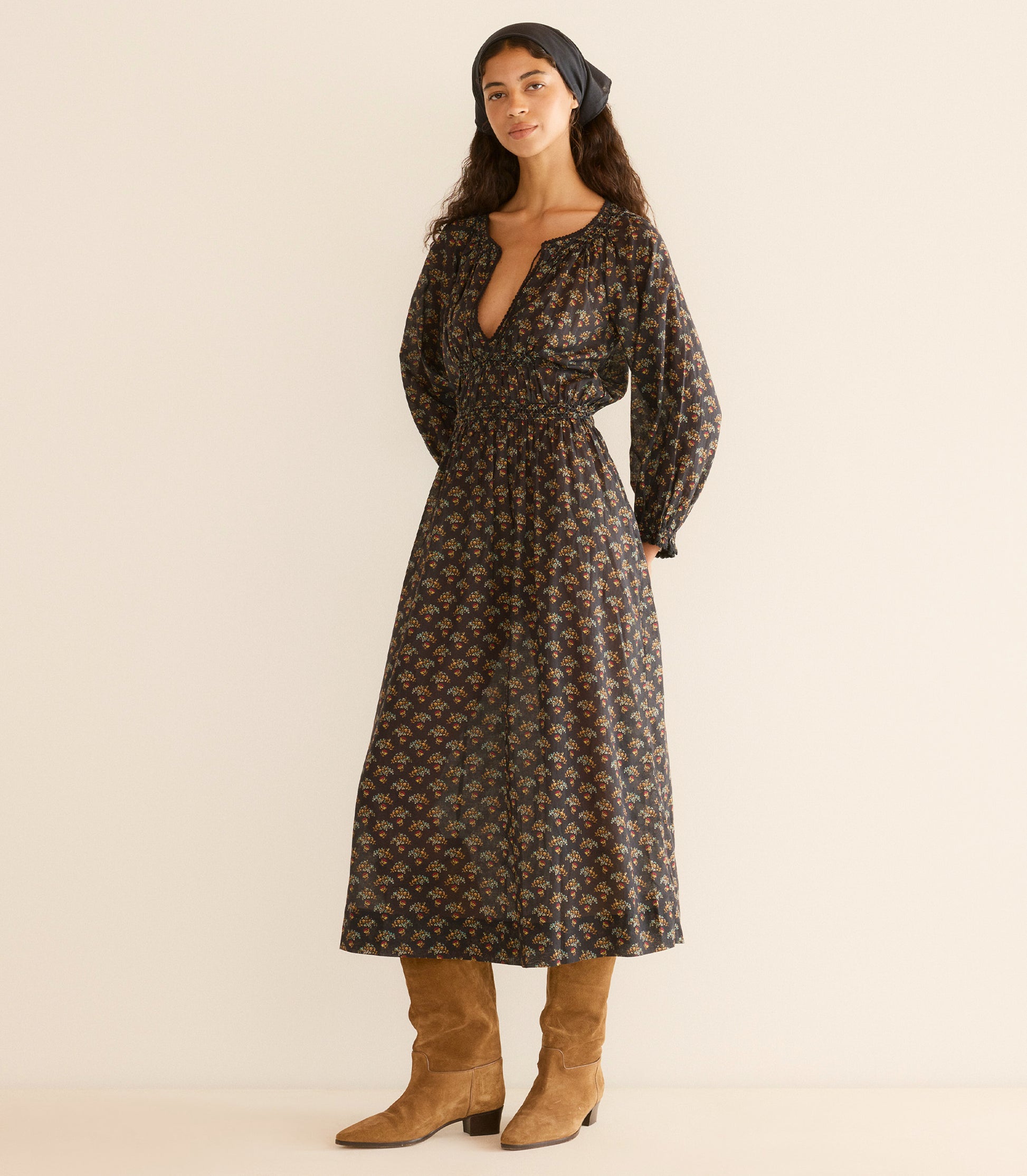 Woman wearing a floral dress with long sleeves, standing against a plain background. 3

