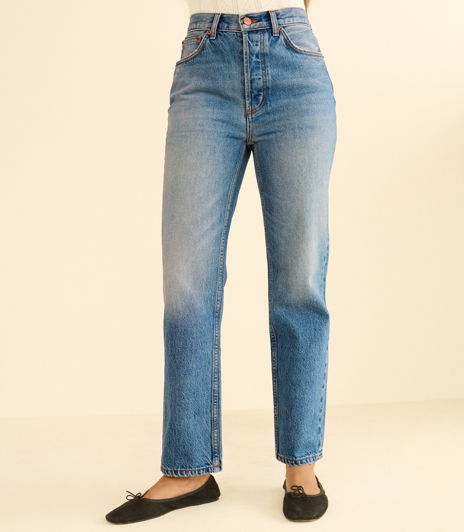 Blue jeans worn by a person on a beige background 1
