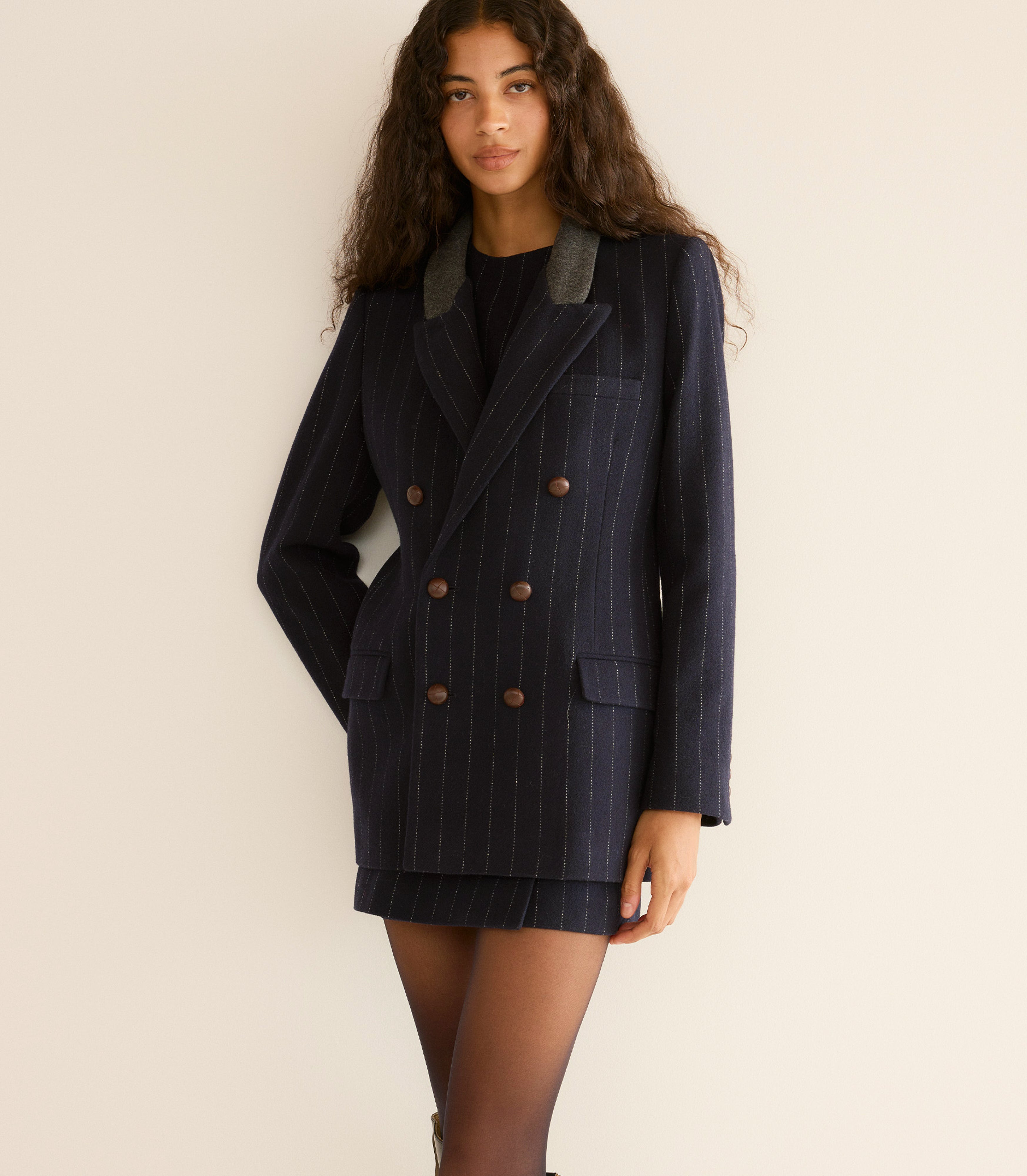 Woman wearing a navy pinstripe blazer with a matching skirt.