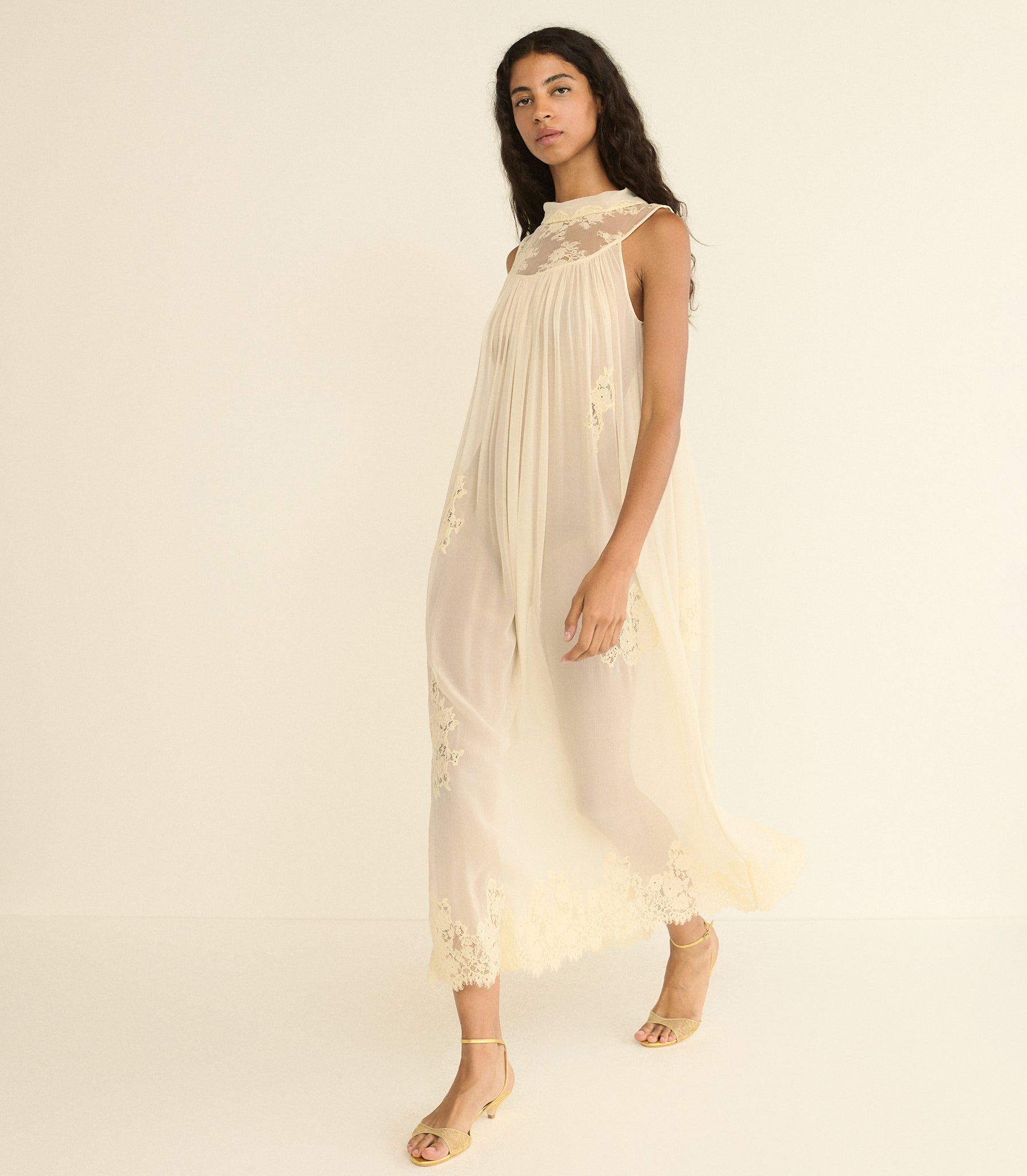 Woman wearing a off white lace dress against a plain background 1
