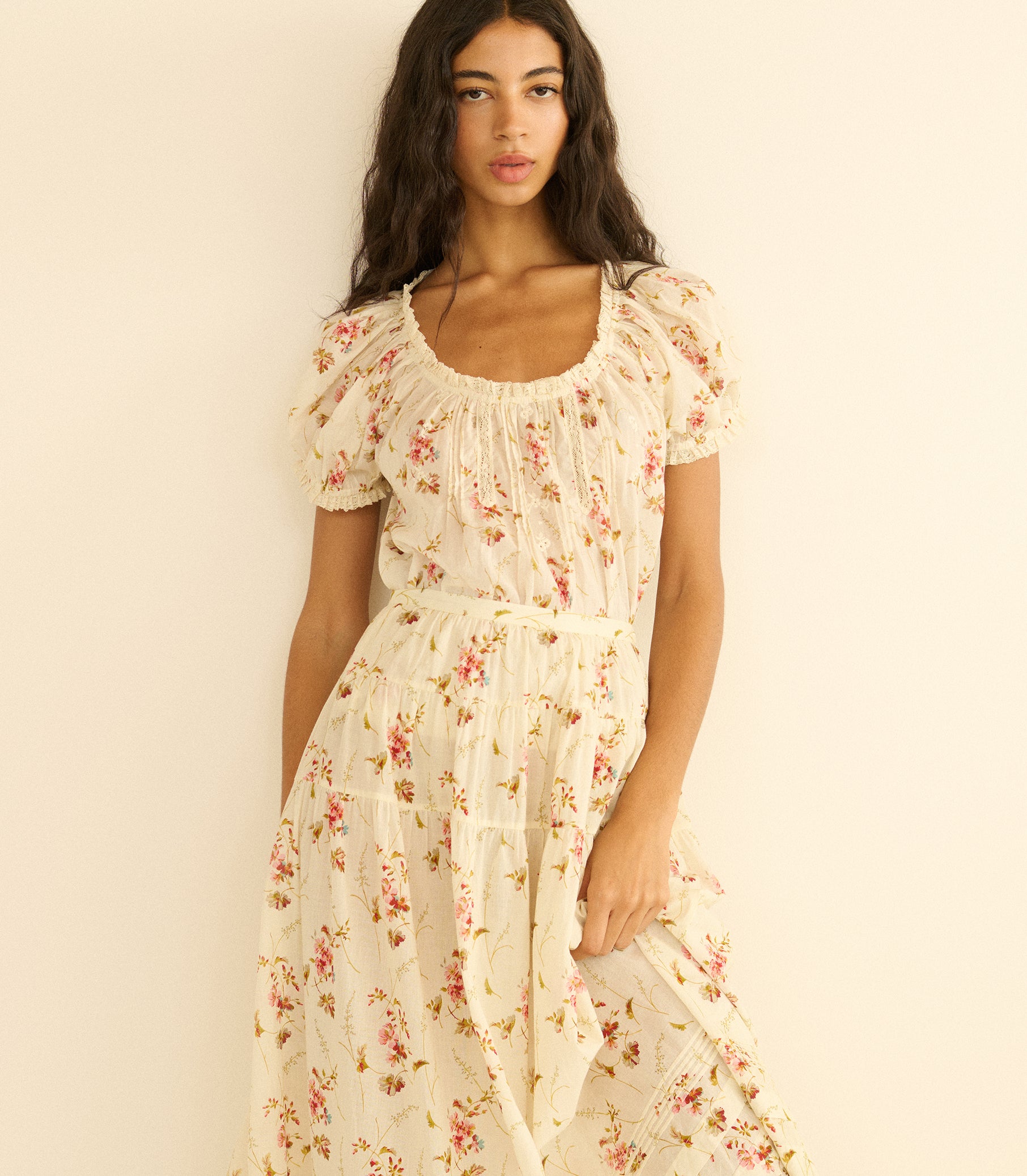 Woman wearing a floral blouse and matching skirt against a plain background 5
