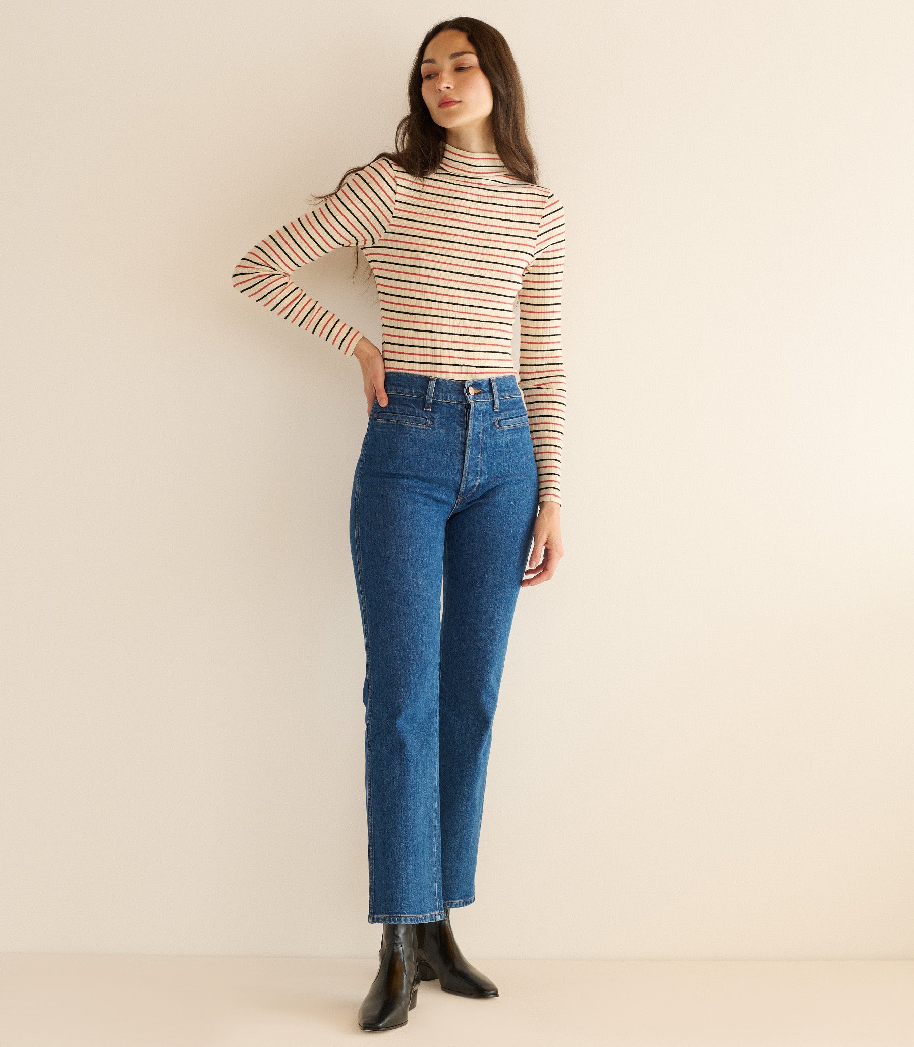 Woman wearing a striped long-sleeve top and blue jeans against a beige background 3

