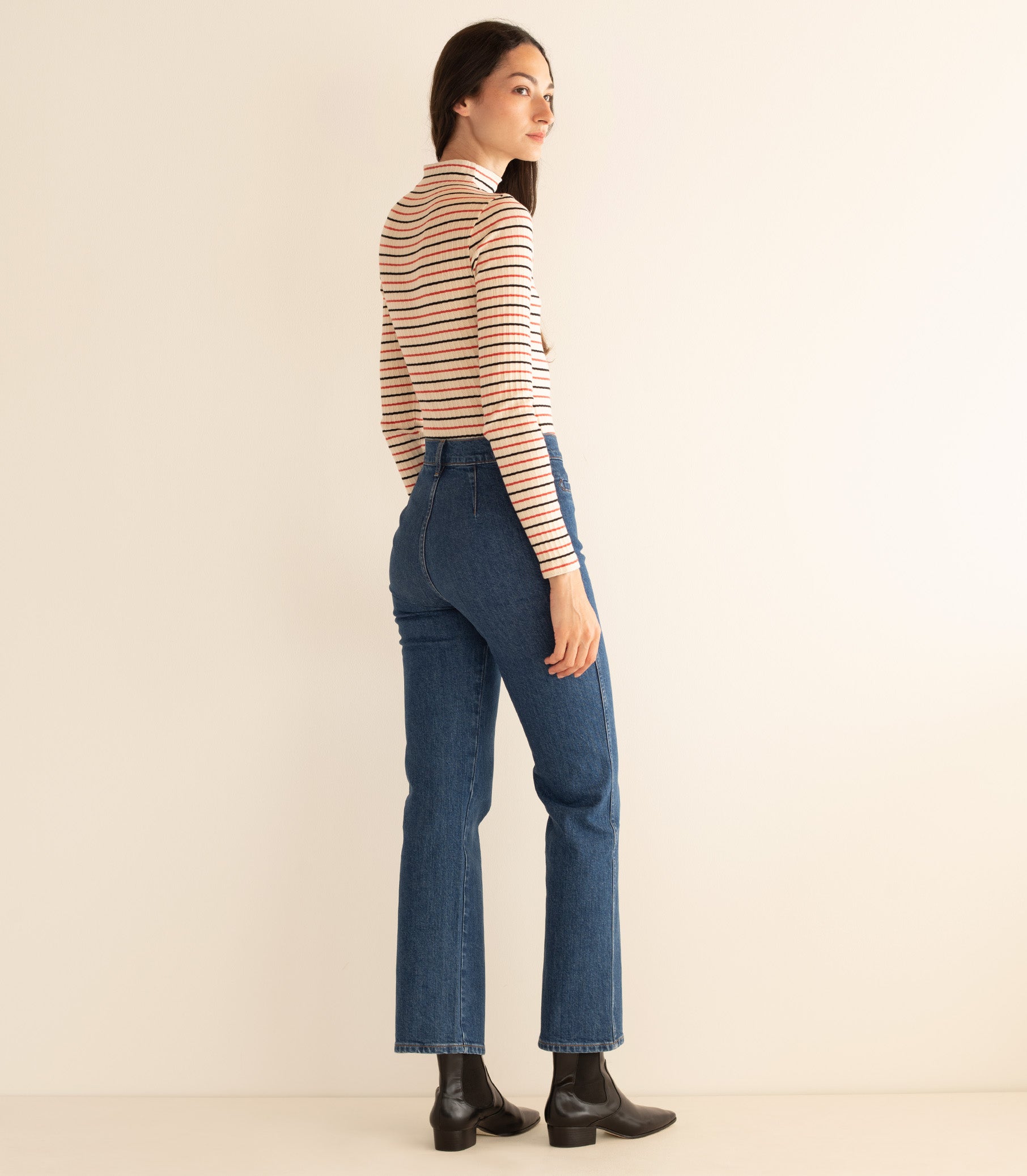 Woman wearing a striped long-sleeve top and blue jeans against a beige background 5
