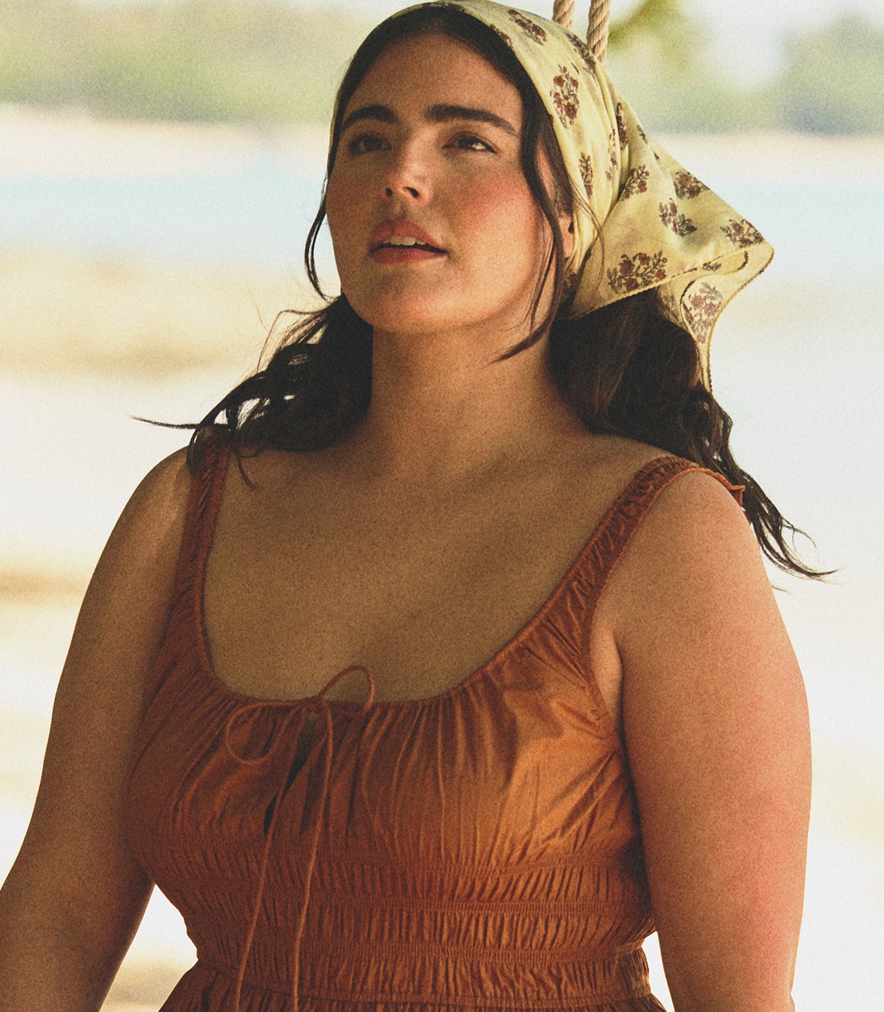 Woman wearing a printed headscarf and orange dress outdoors 1
