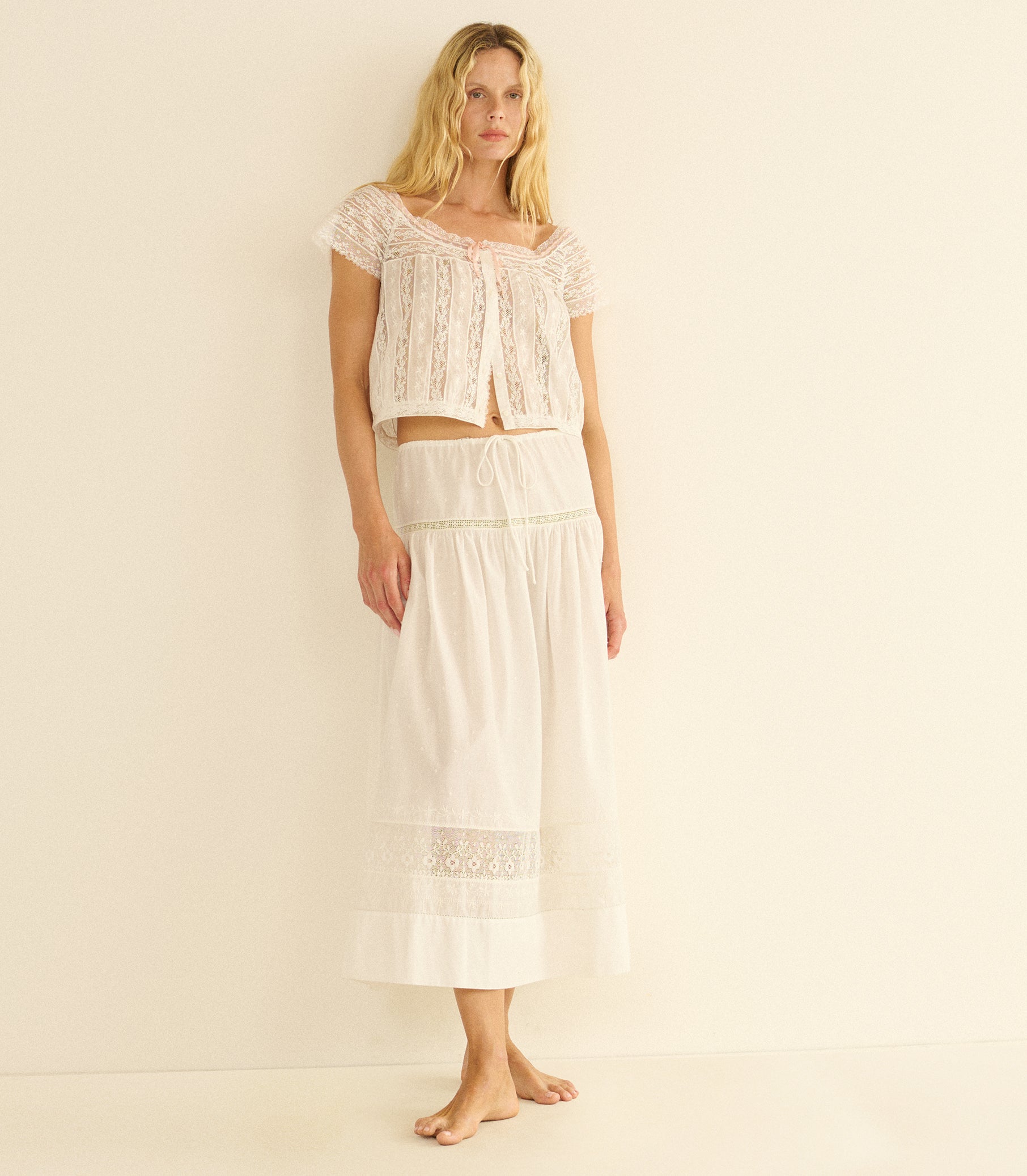 Woman wearing a white lace top and skirt set on a beige background 1
