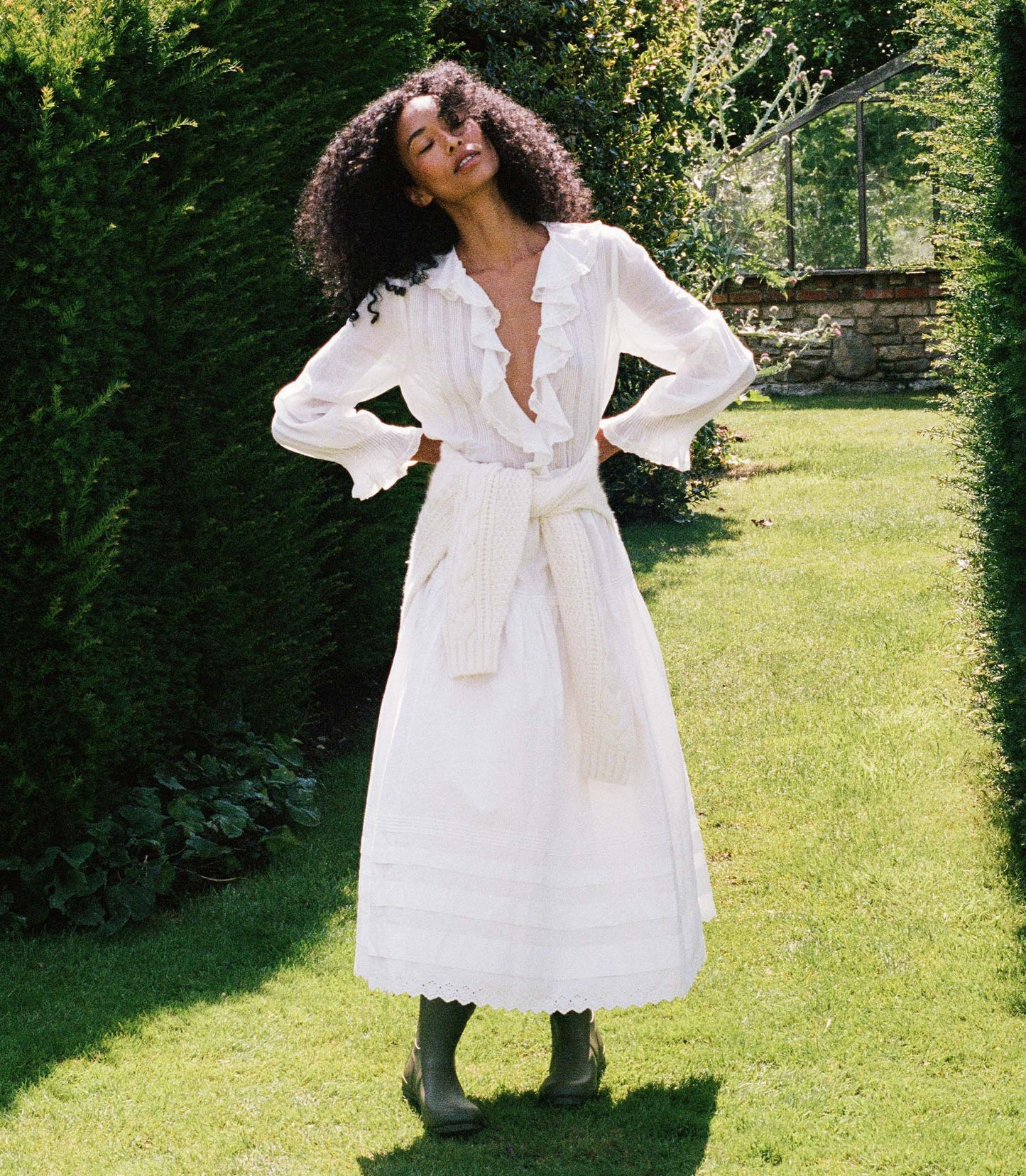 Woman wearing a white blouse and white skirt amongst greenery