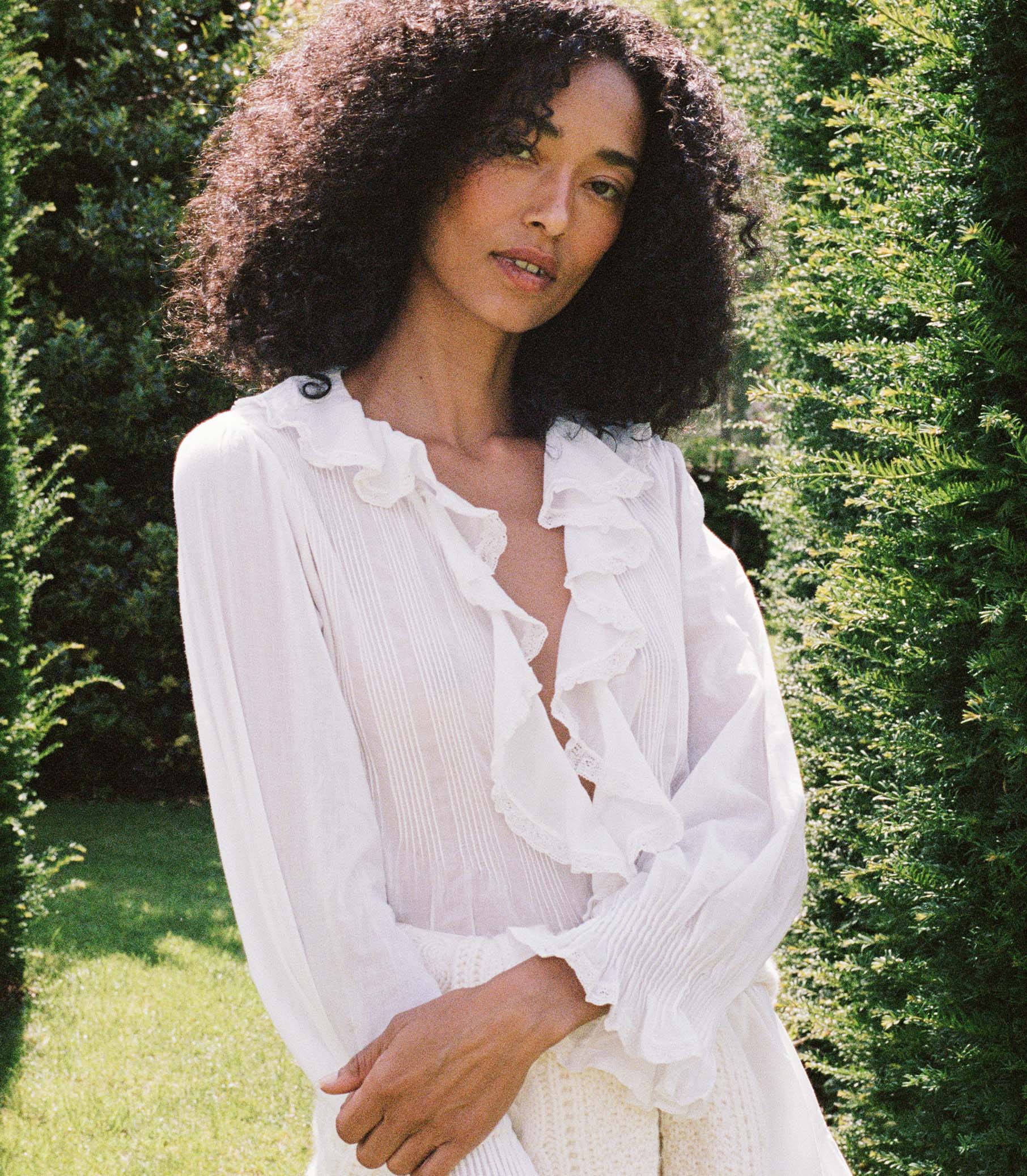 Woman wearing a white blouse and white skirt amongst greenery 5
