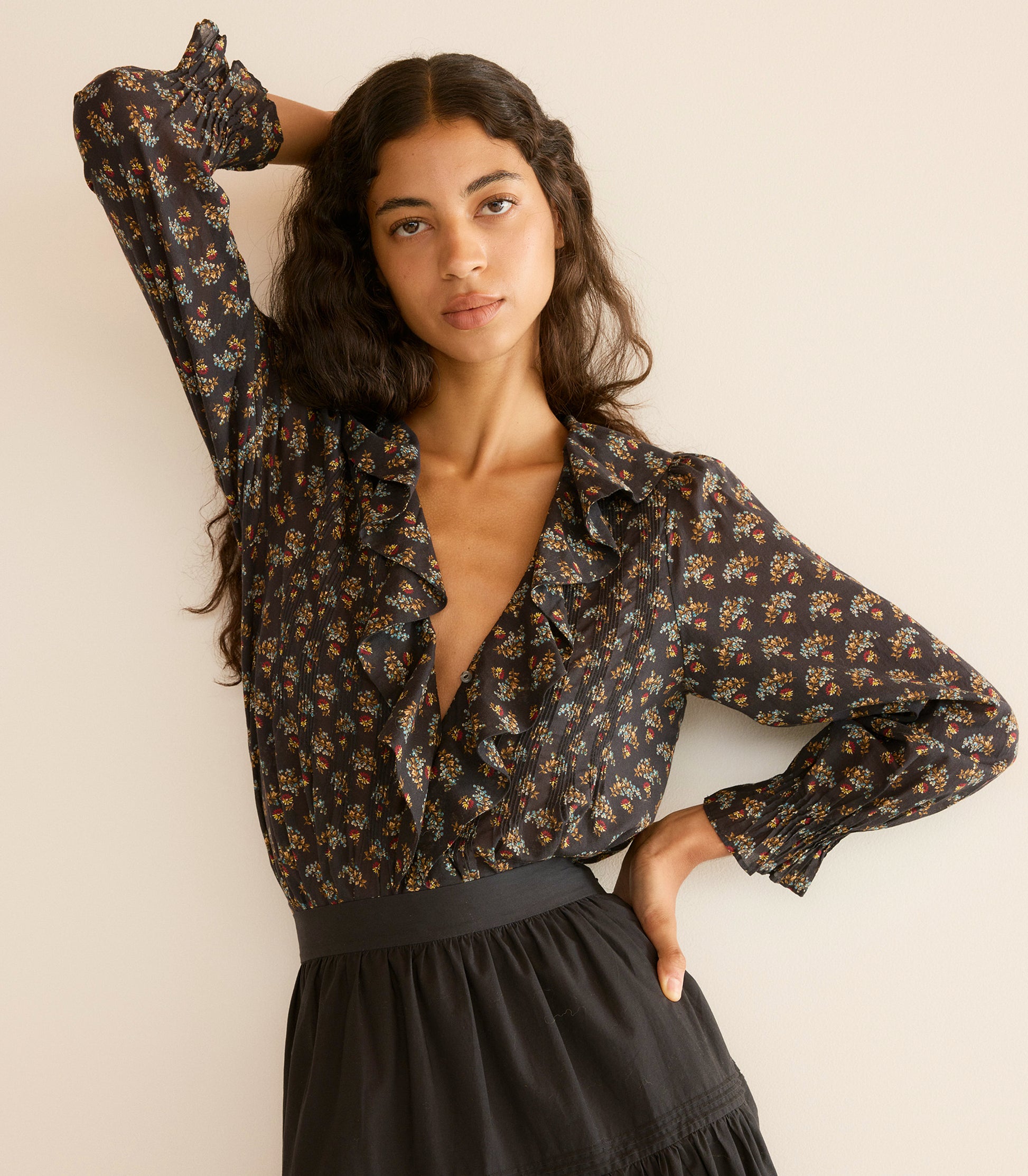 Woman wearing a floral blouse and black skirt against a plain background 3
