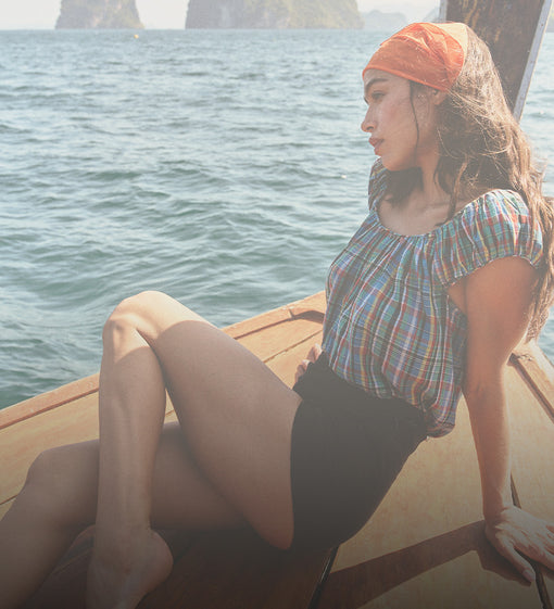 Woman sitting on a boat by the water with an orange headscarf