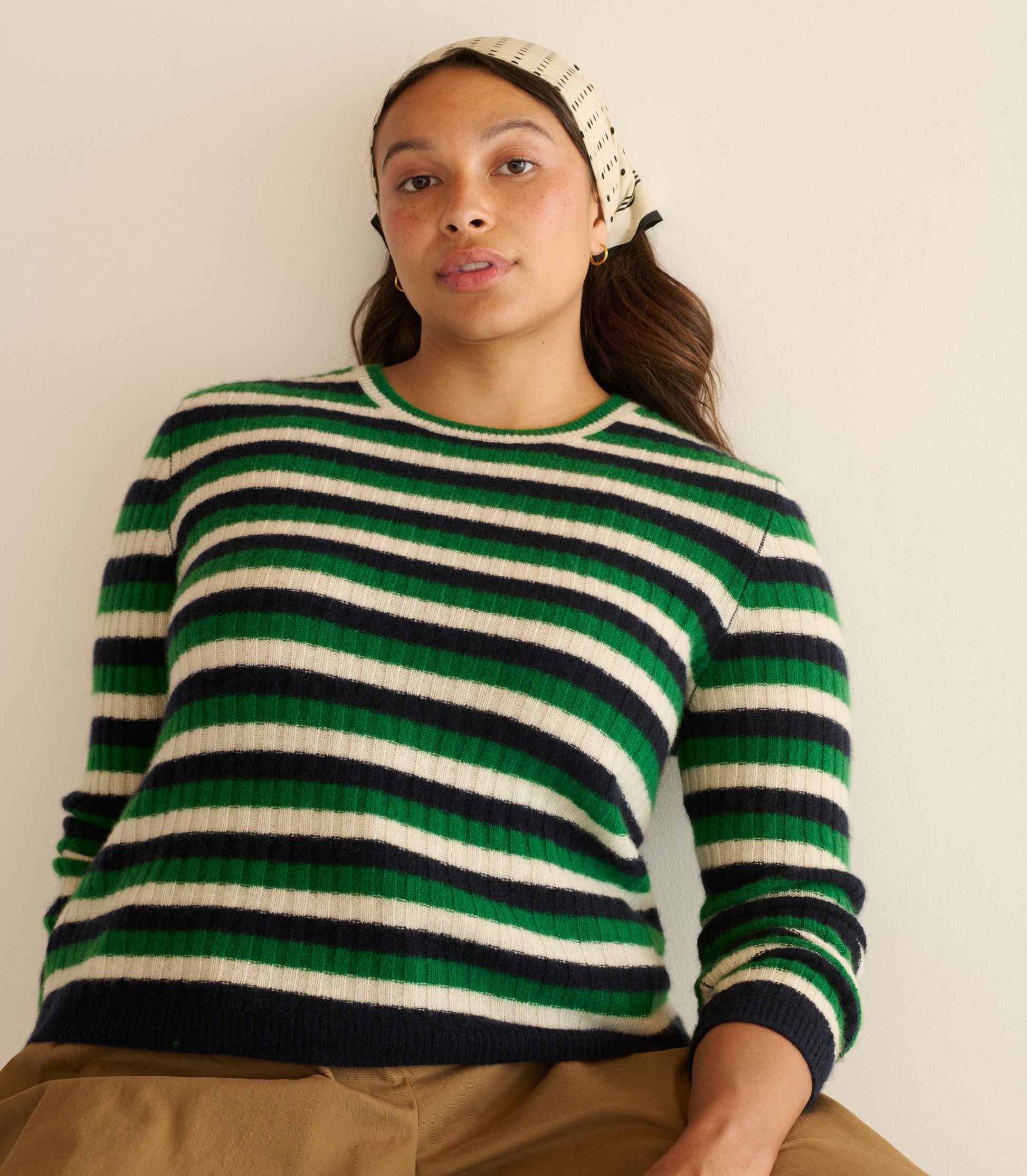Person wearing a green and black striped sweater on a plain background 5
