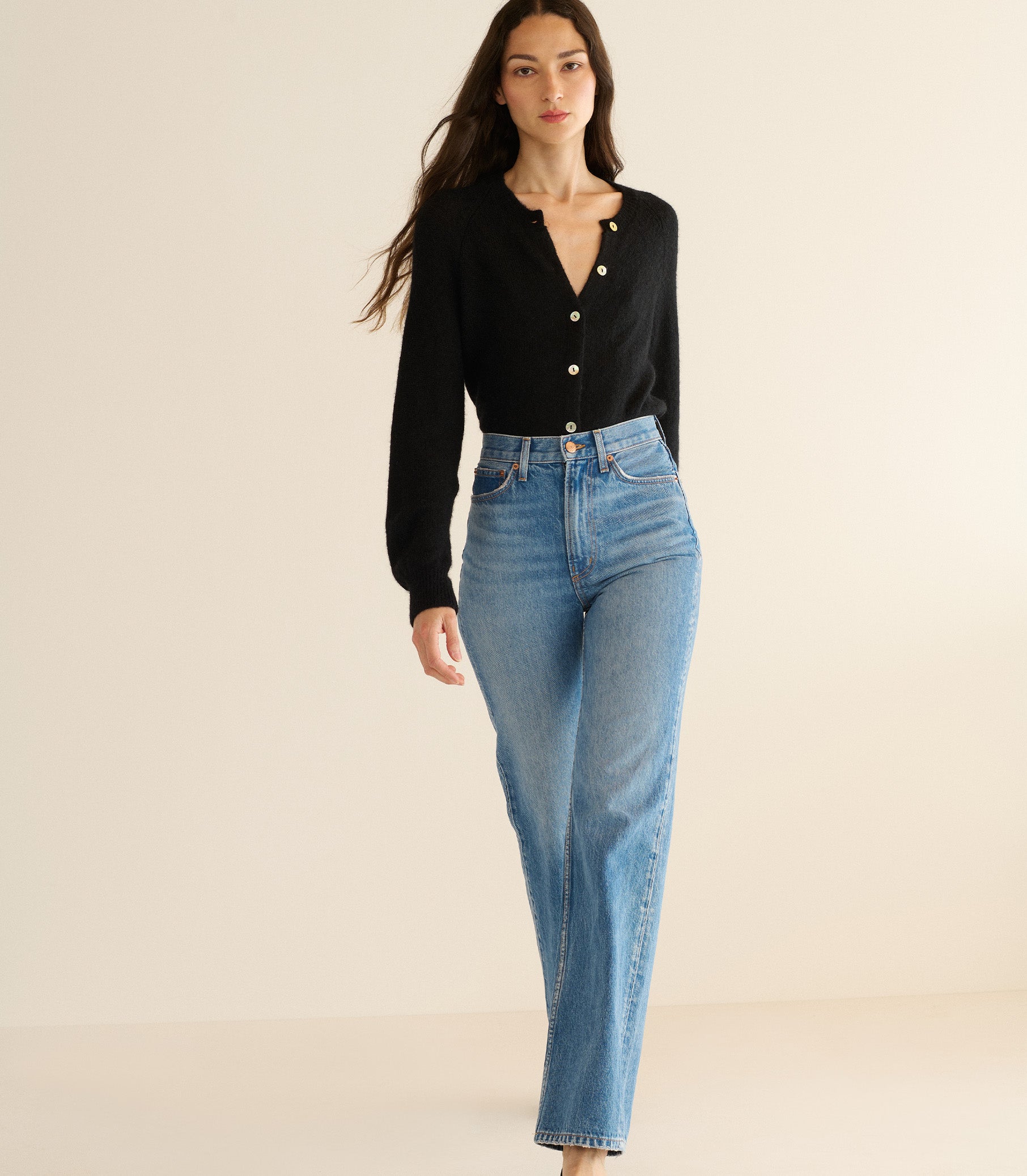 Woman wearing a black cardigan and blue jeans on a beige background 3
