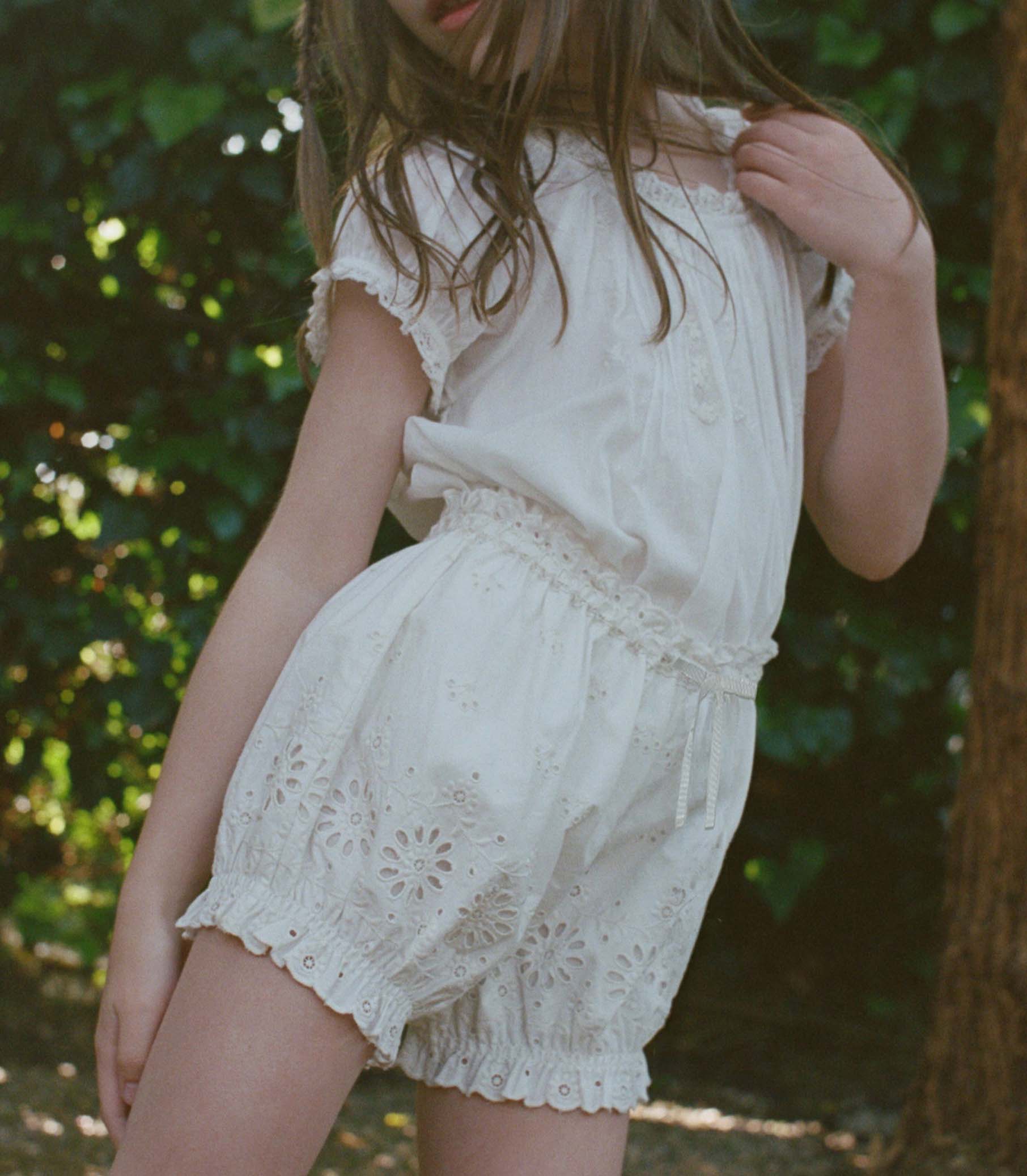 Kid wearing white lace shorts in a natural setting 1
