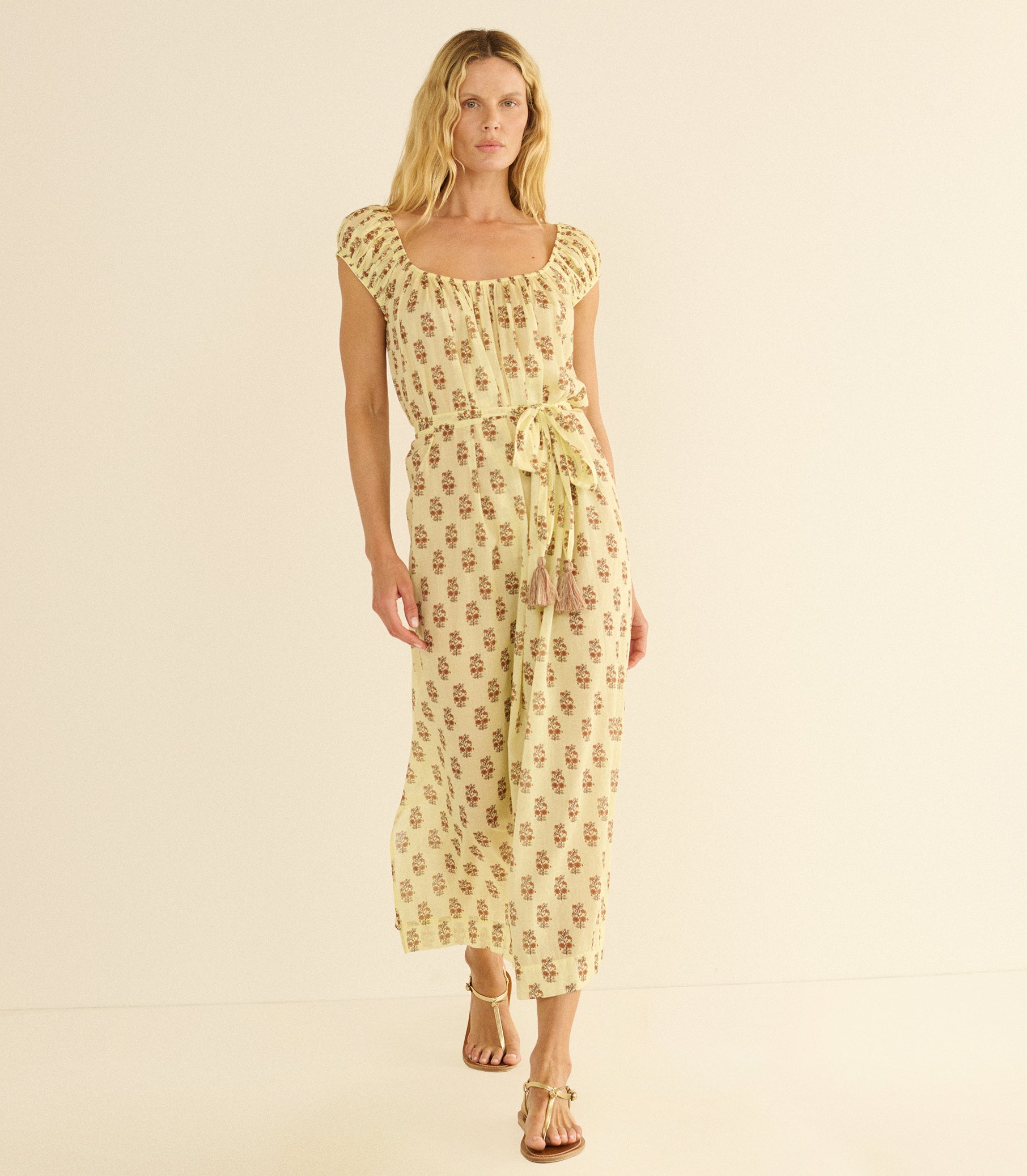 Woman wearing a yellow floral dress on a beige background 1

