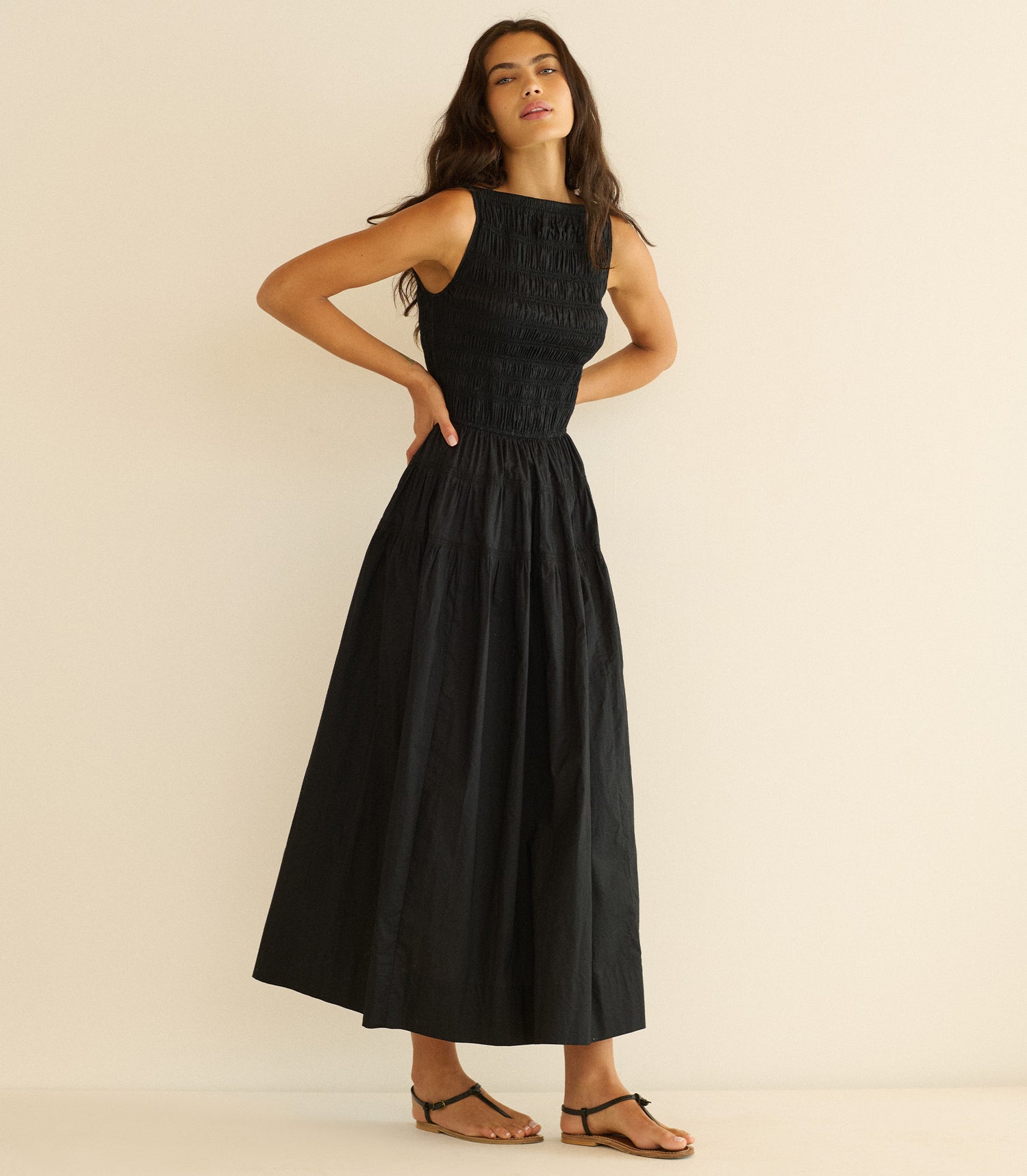 Woman wearing a black sleeveless dress against a beige background