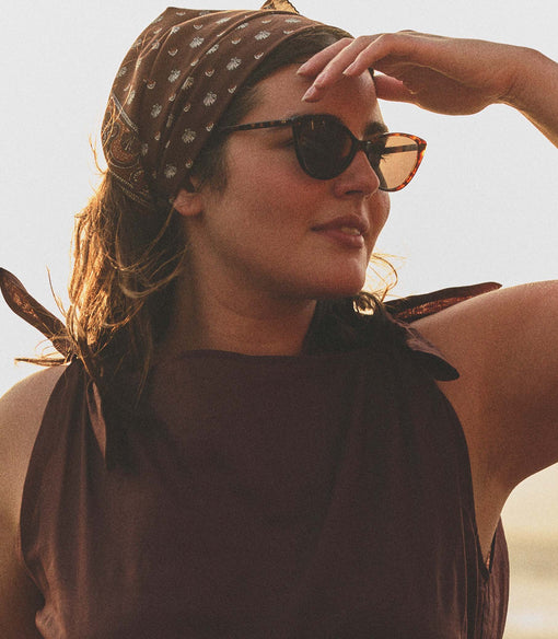 Woman wearing sunglasses and a headscarf with a blurred background