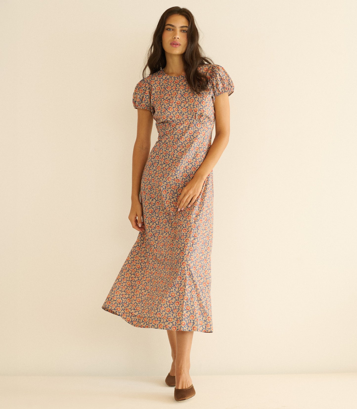 Woman wearing a floral dress against a beige background