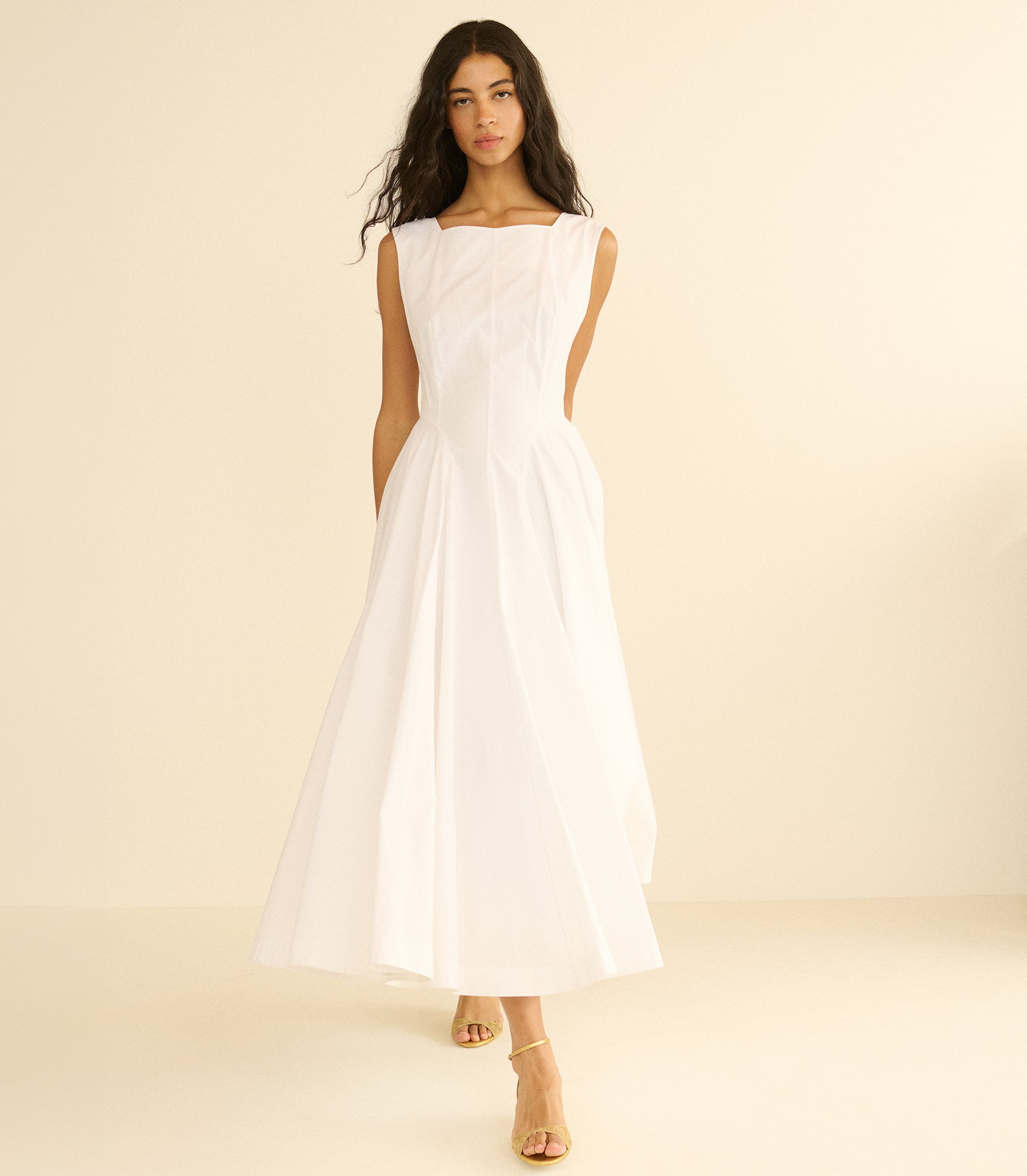 Woman wearing a long white dress against a beige background 2
