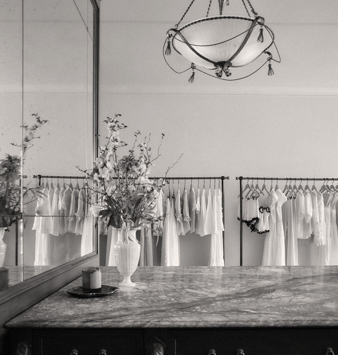 Clothing store interior with racks of white shirts, a mirror, and decorative elements.