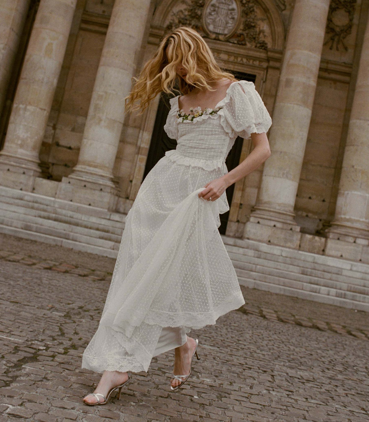 Woman in a white pin dot dress standing in front of classical architecture