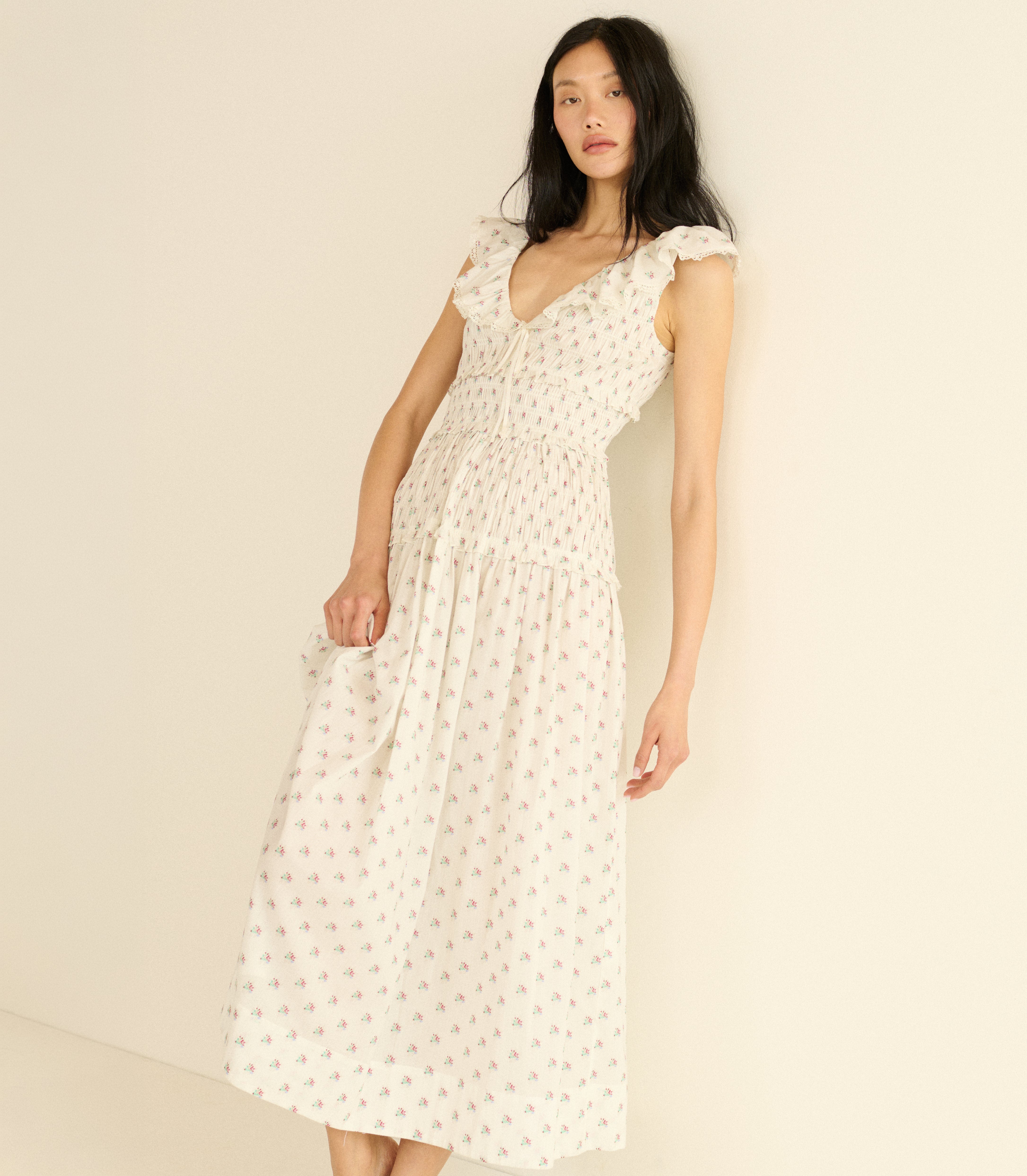 Woman wearing a white floral dress against a beige background