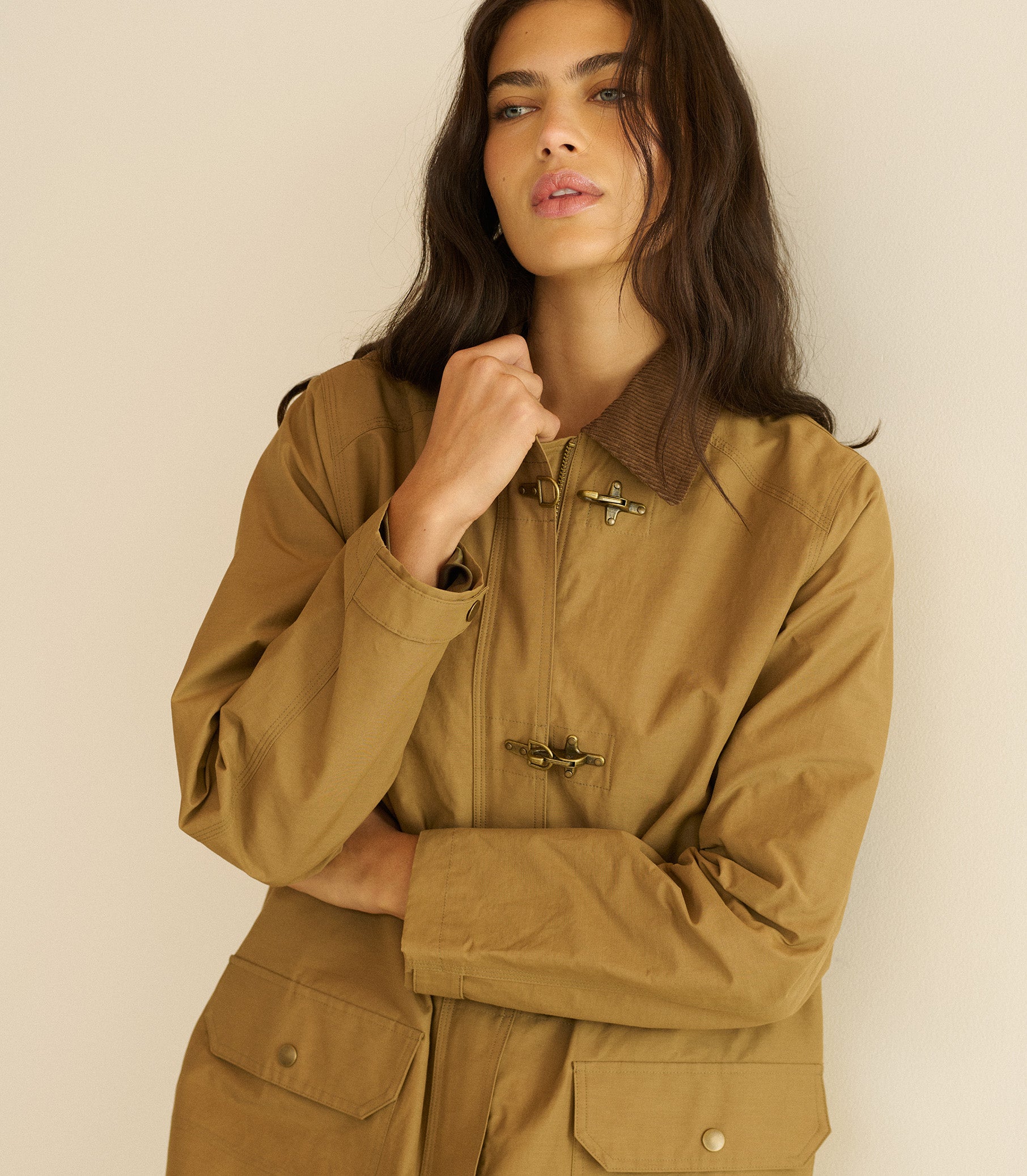 Woman wearing a brown jacket against a beige background 1
