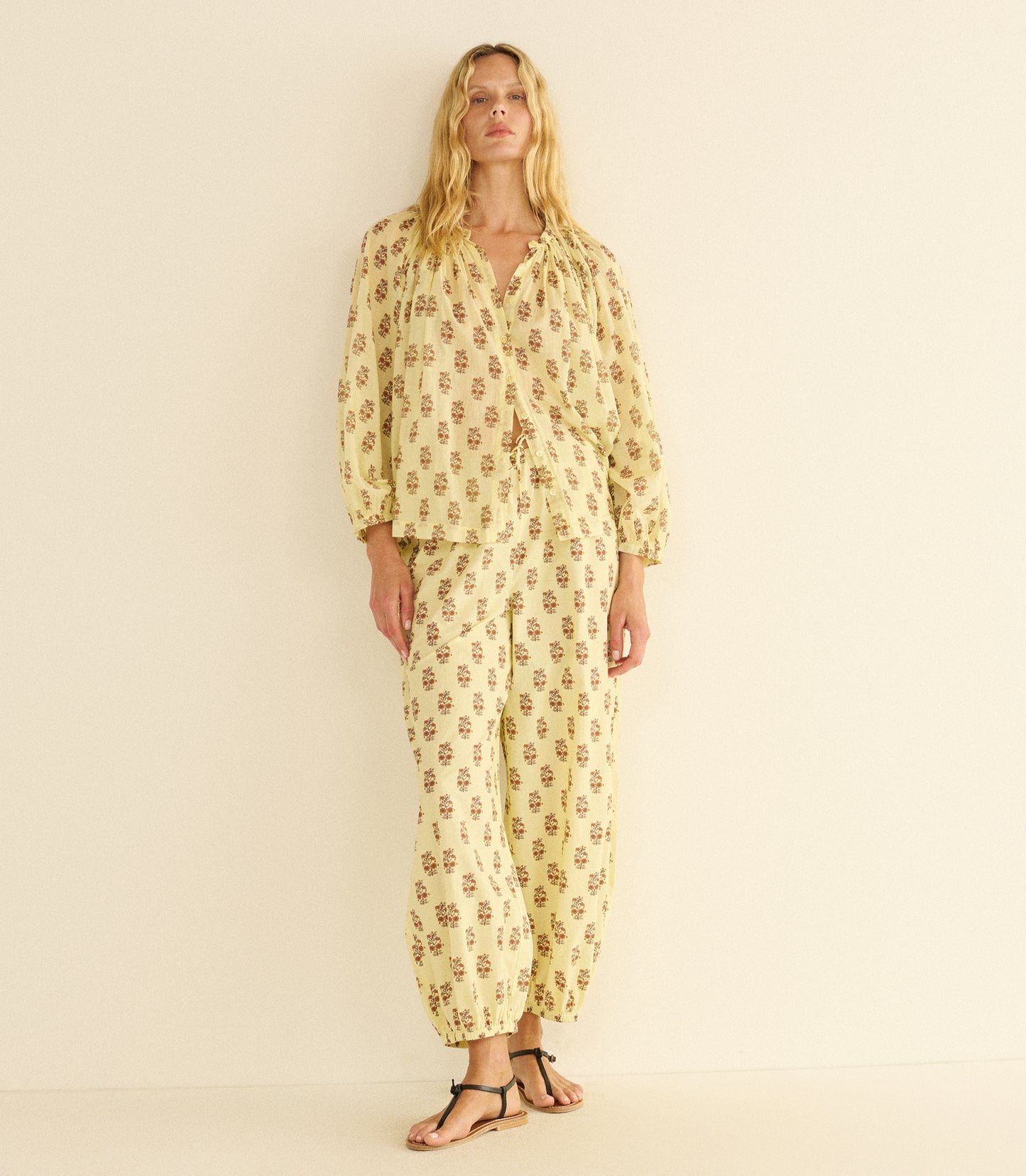Woman wearing a yellow patterned outfit on a beige background